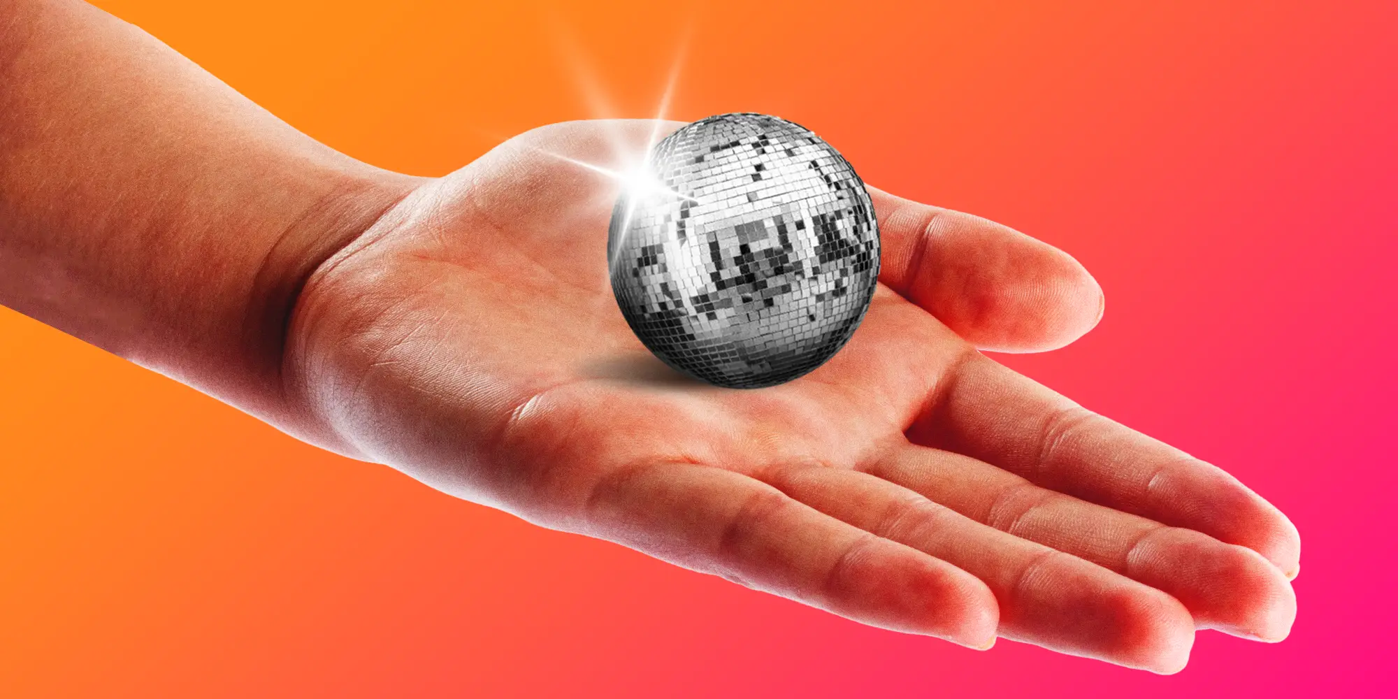 A hand holding a small disco ball in palm