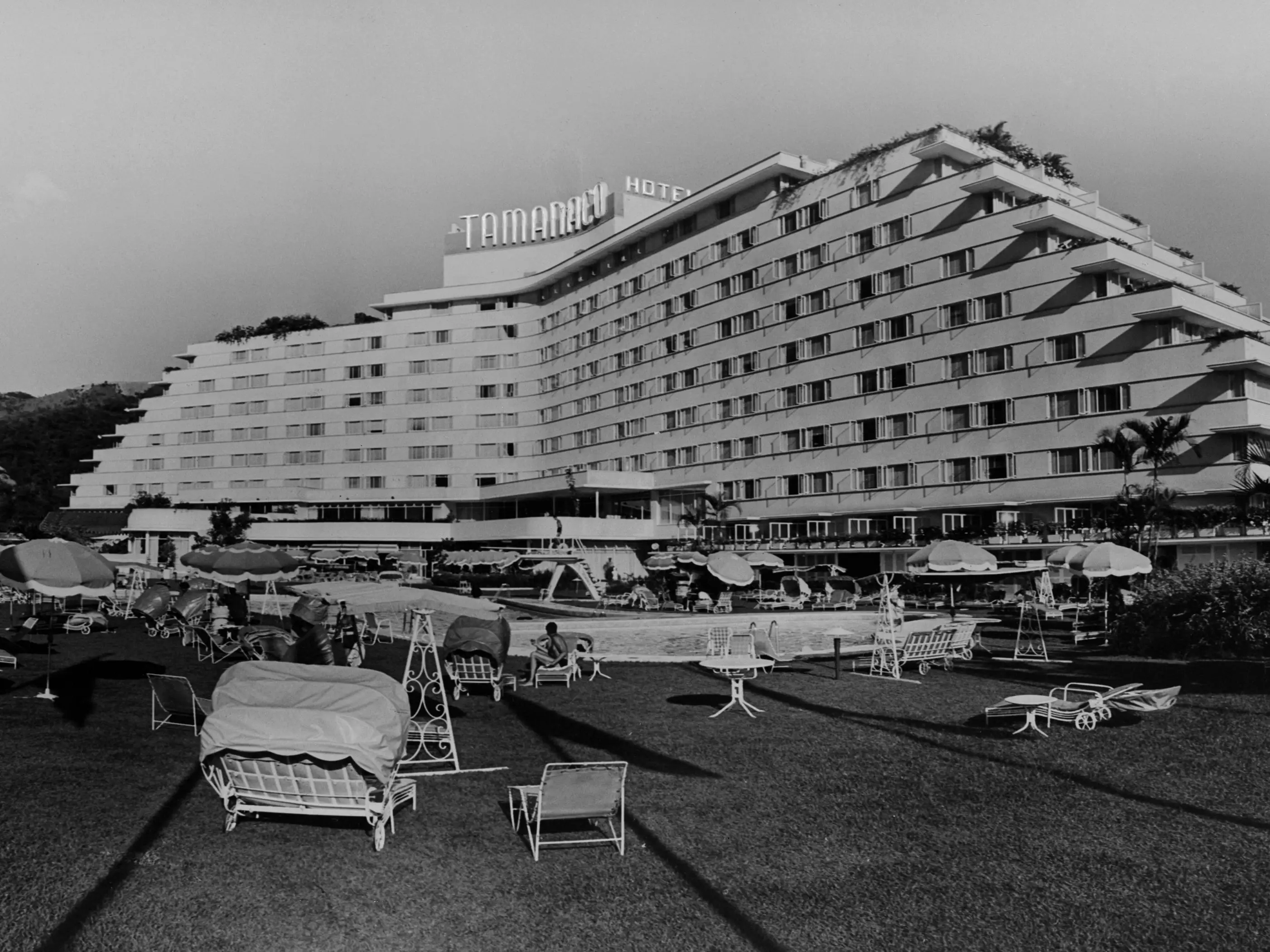 Exterior view of the pool/resort area, with guests lounging, at the Tamanaco Hotel in Caracas, Venezuela, 1958.