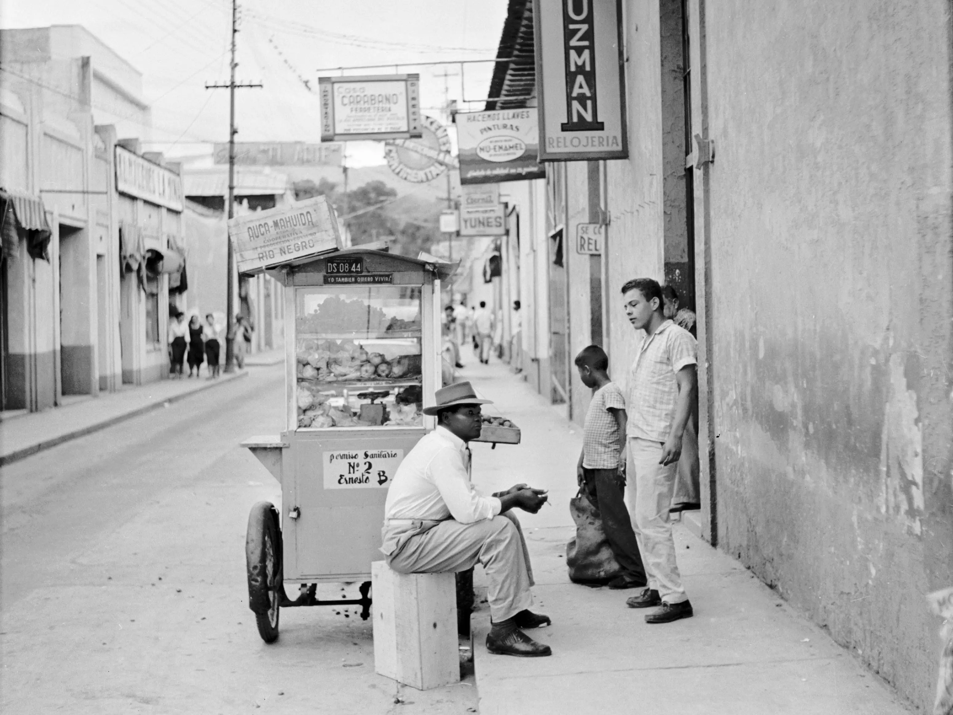 A street vendor sitting by a mobile hot food stall in Maracay, Venezuela, circa 1955