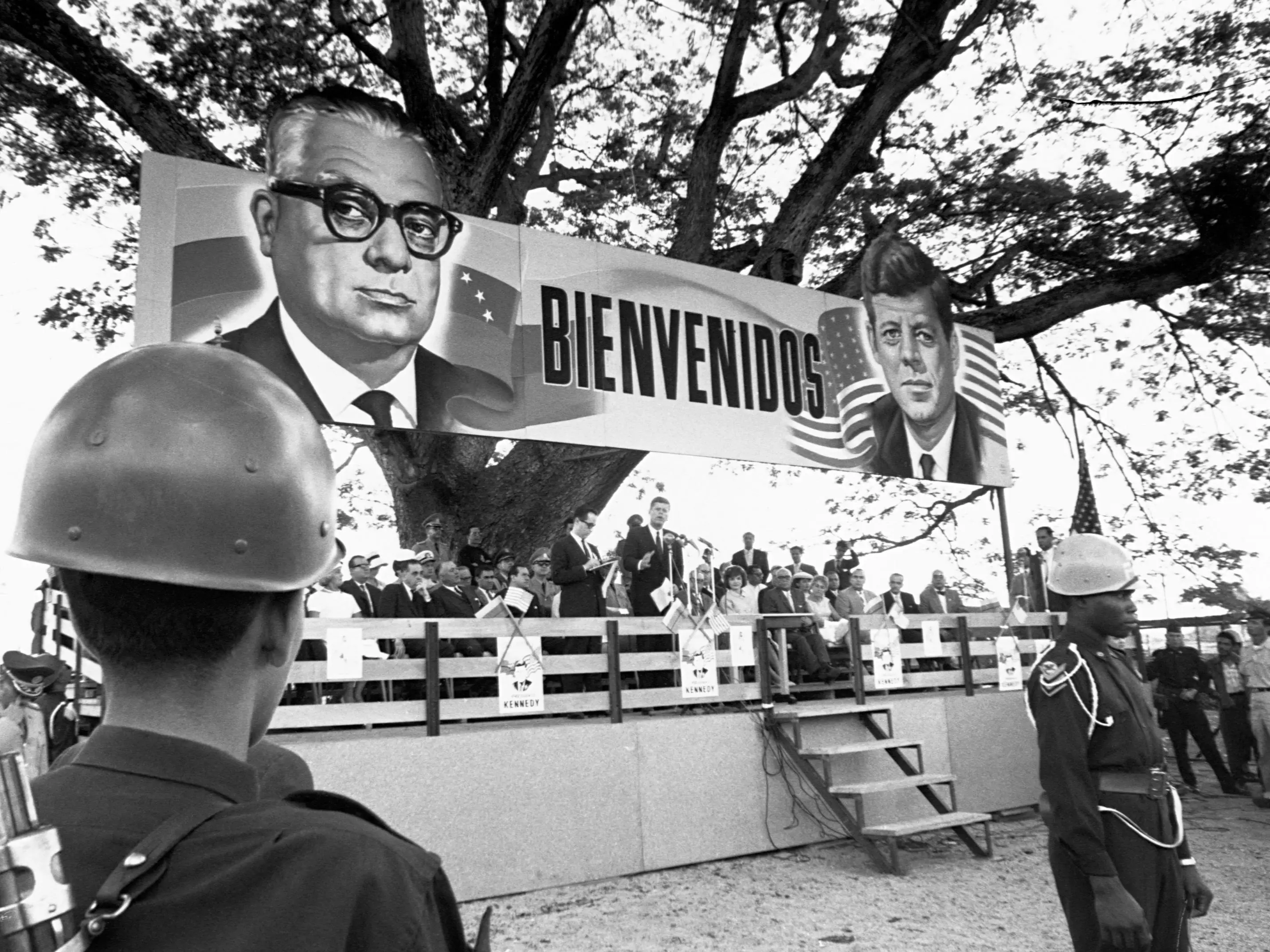 President Kennedy speaking in La Marita, Venezuela. Above him is a sign welcoming him. December 15, 1961.