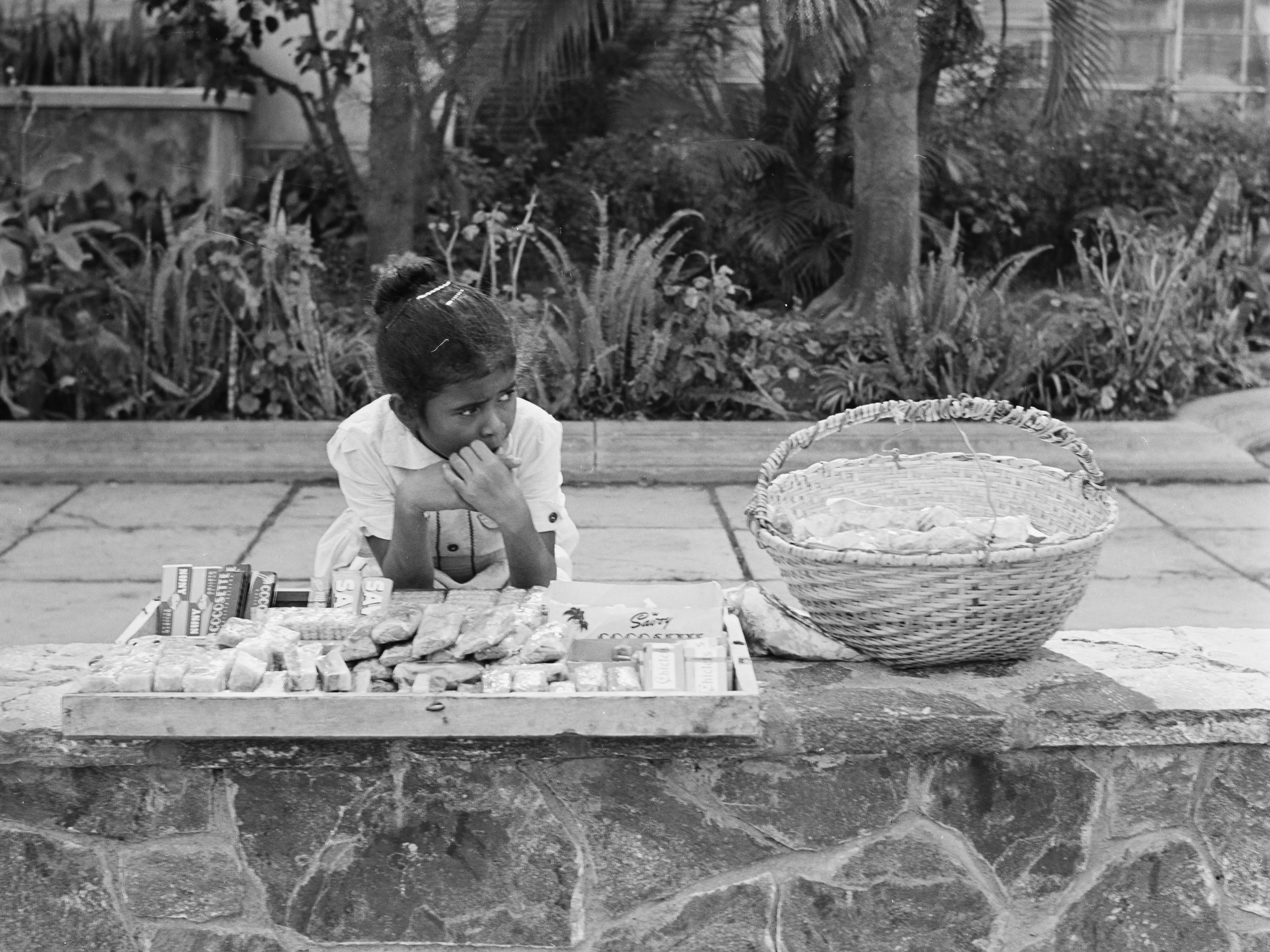 A little girl sells candy bars and sweets by the side of a road in Caracas, Venezuela, circa 1955.