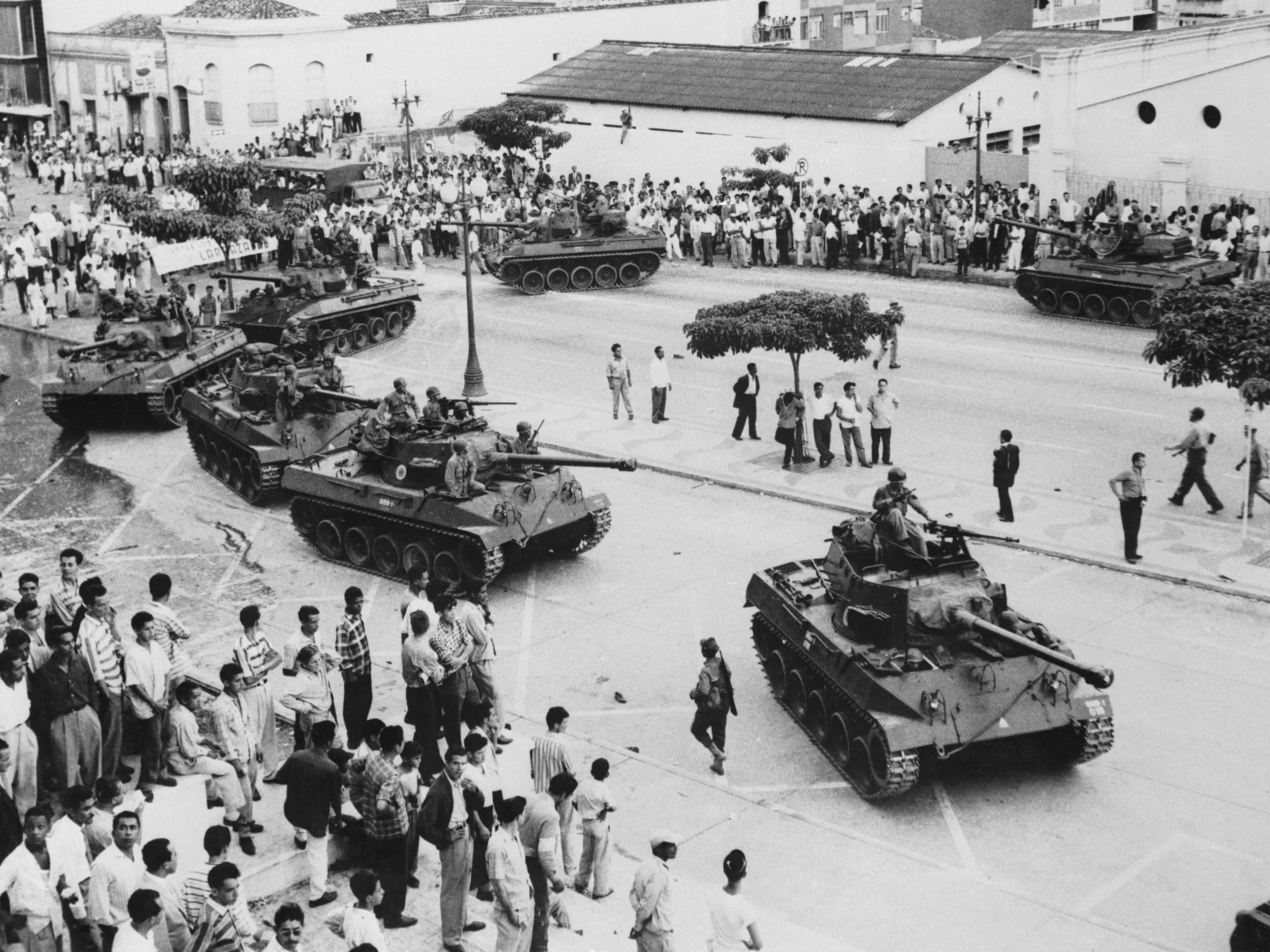 9/7/1958-Caracas, Venezuela-Venezuelan civilians look on as loyal army tanks move in to quell a revolt by military police here Sept. 7. Twenty persons were killed and 120 injured during the few hour rebellion. Rear Admiral Wolfgang Larrazabel, junta leader, asked Sept. 8 that nearly 1,000,000 workers to end their general strike after agreeing to their demands to punish severely leaders of the revolt