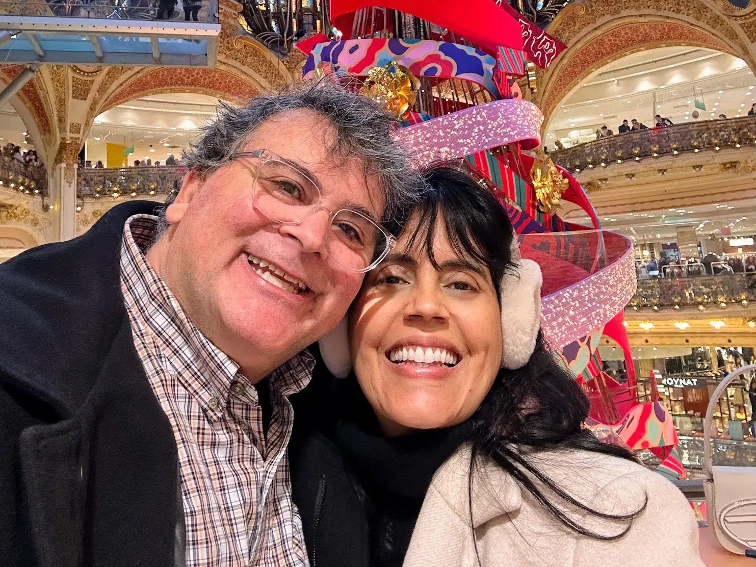 Author Mar Yvette and her husband smiling in front of a display at Mar Aram Galeries with ribbons, sparkles