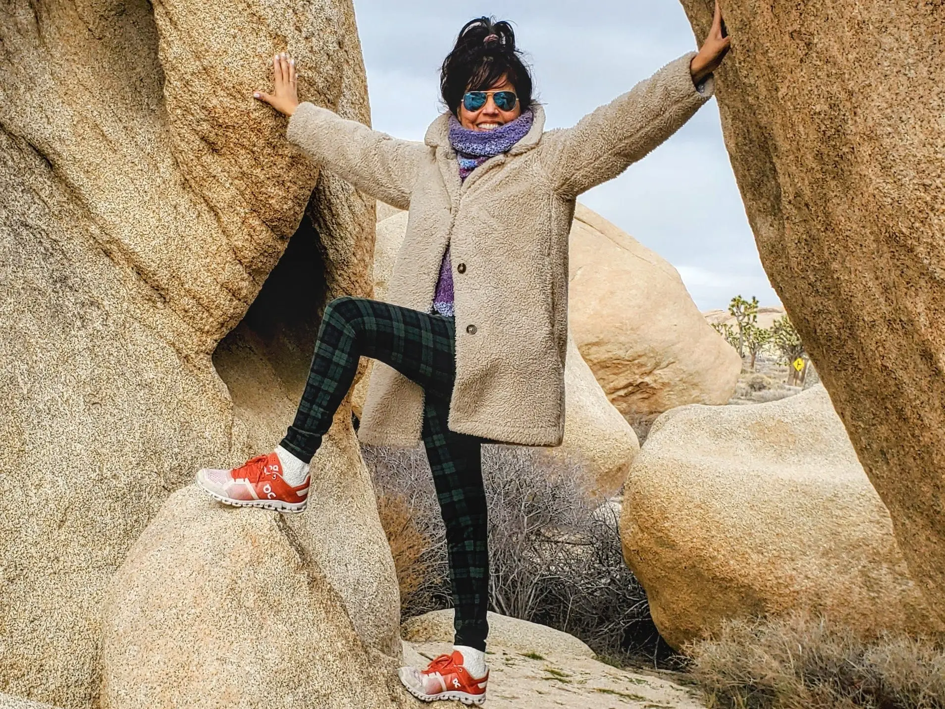 Woman with hat, sunglasses posed between rock formations