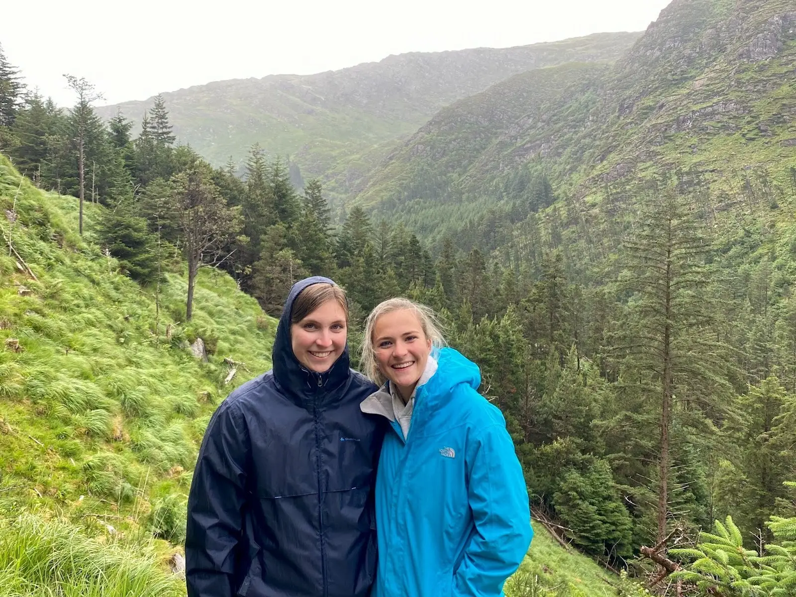 Hannah and a friend wearing raincoats while standing in the mountains.