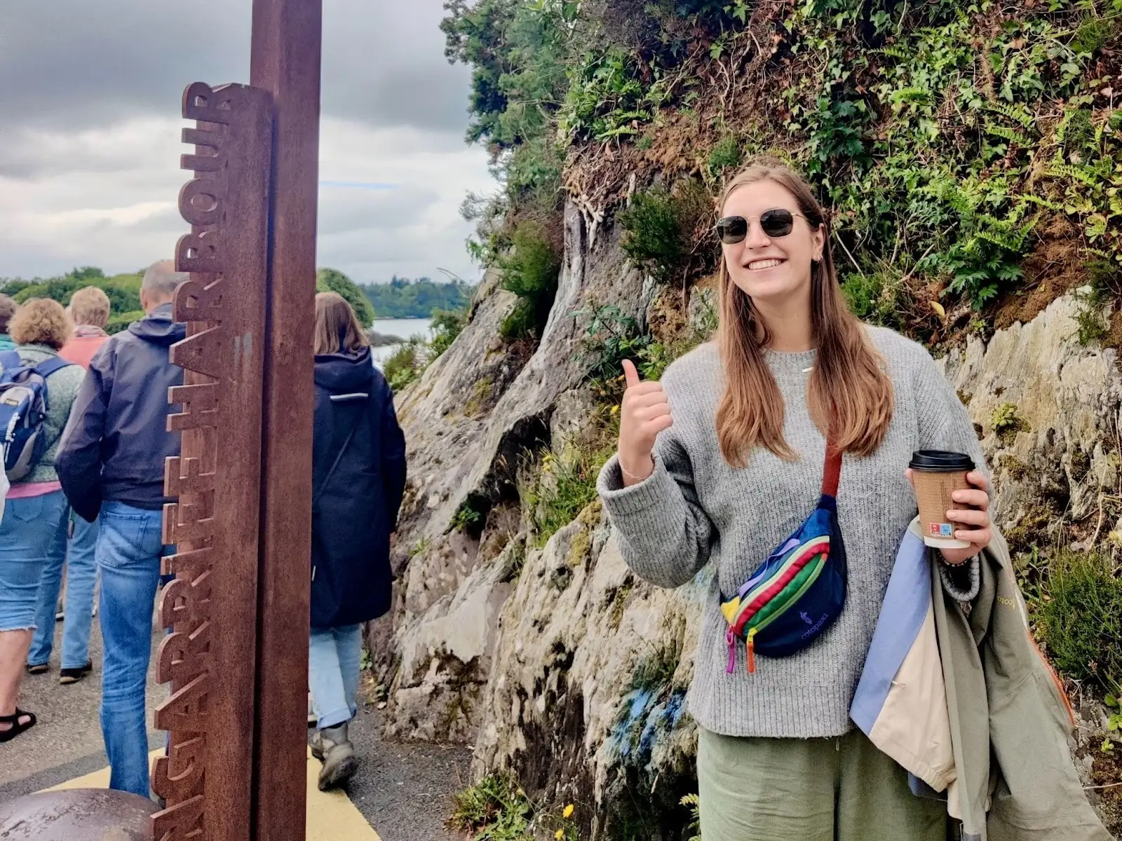 Hannah wears a sweater and holds a jacket in her arms.