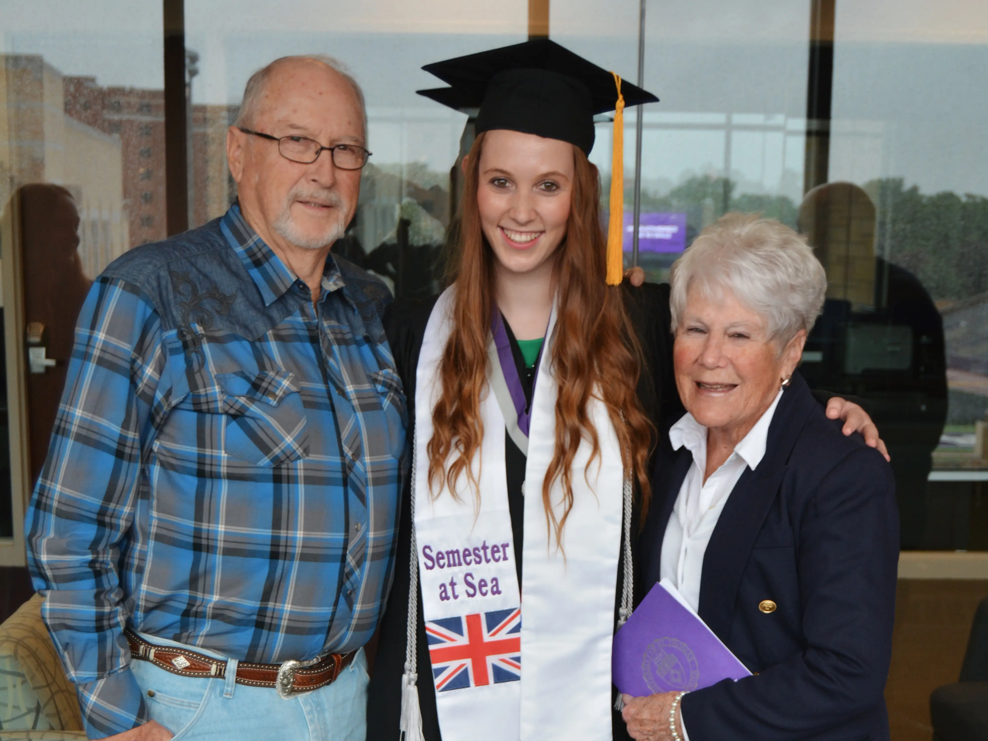 Author Allie Hubers in graduation cap with grandparents, smiling