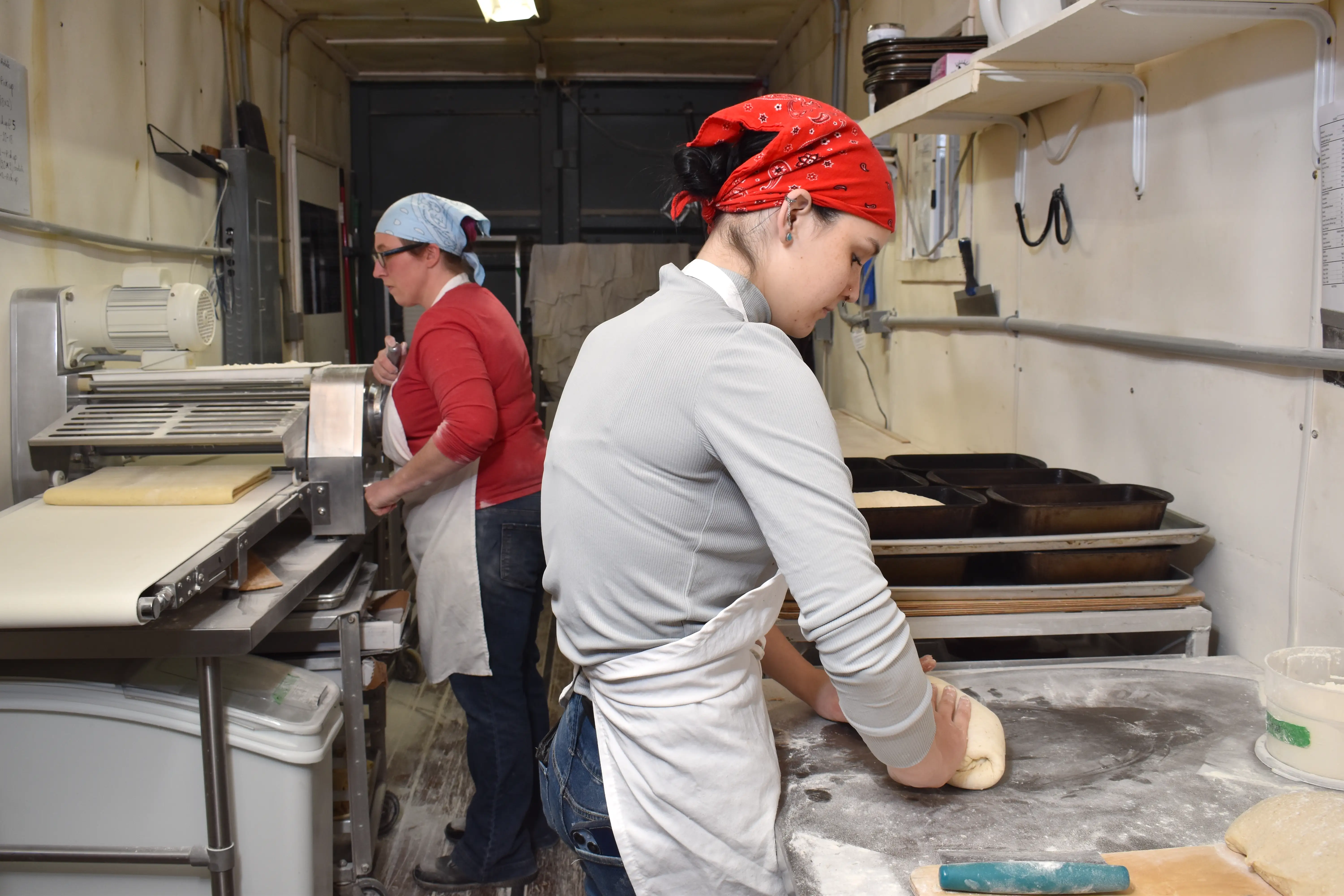 Two woman shaping bread in a shipping container.