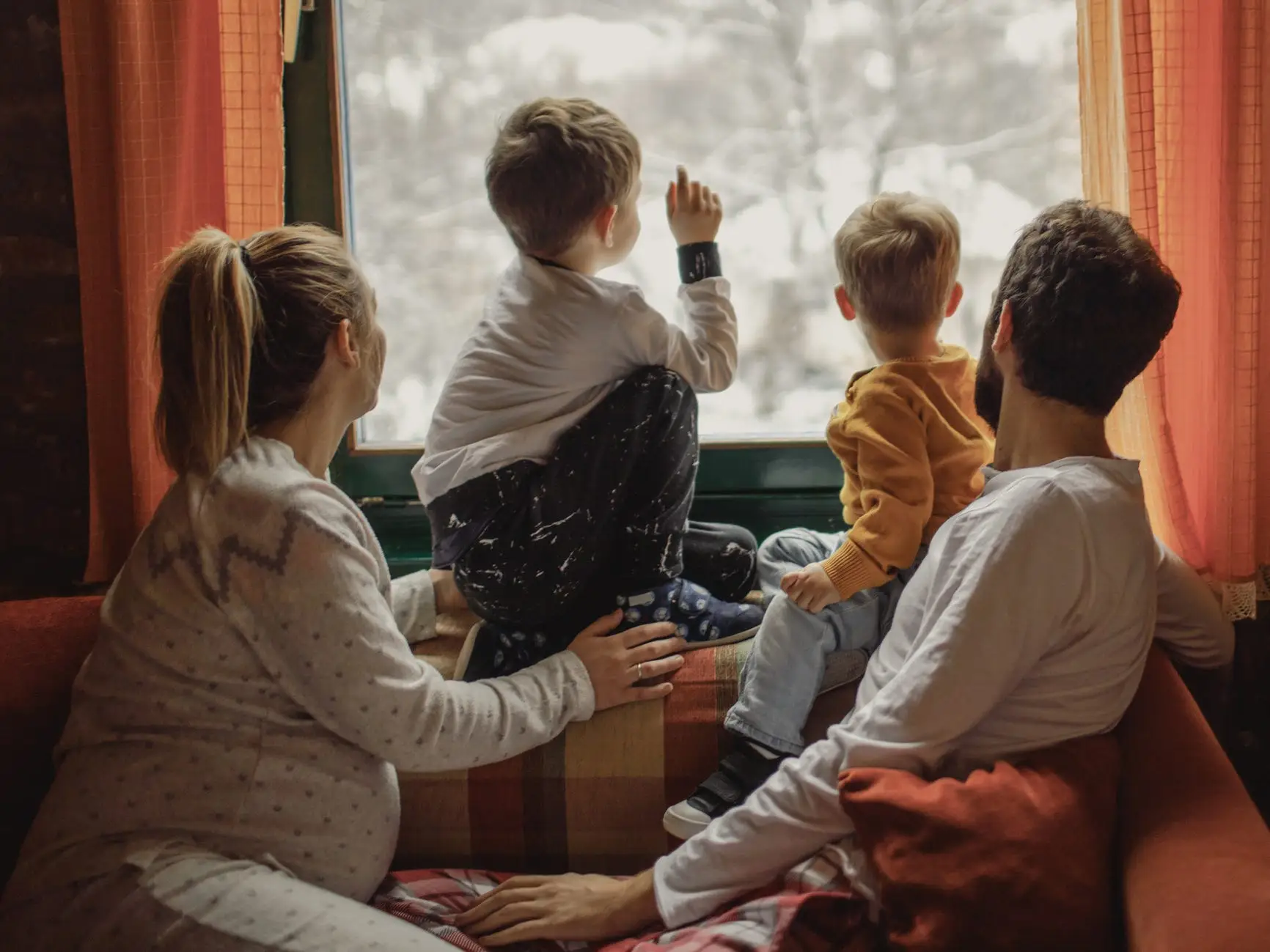 Family looking out the window at snow.