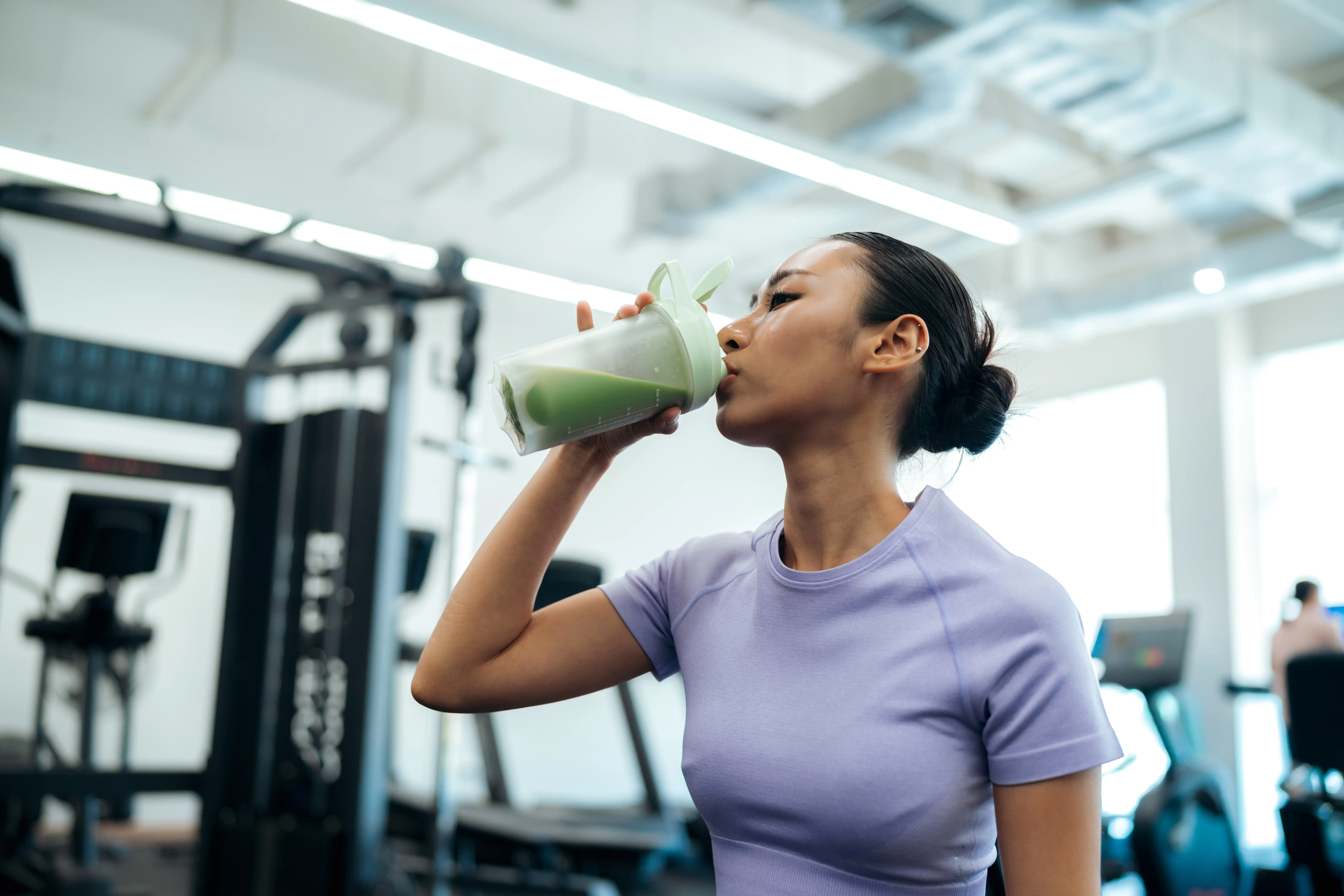 a woman drinking a protein shake in the gym