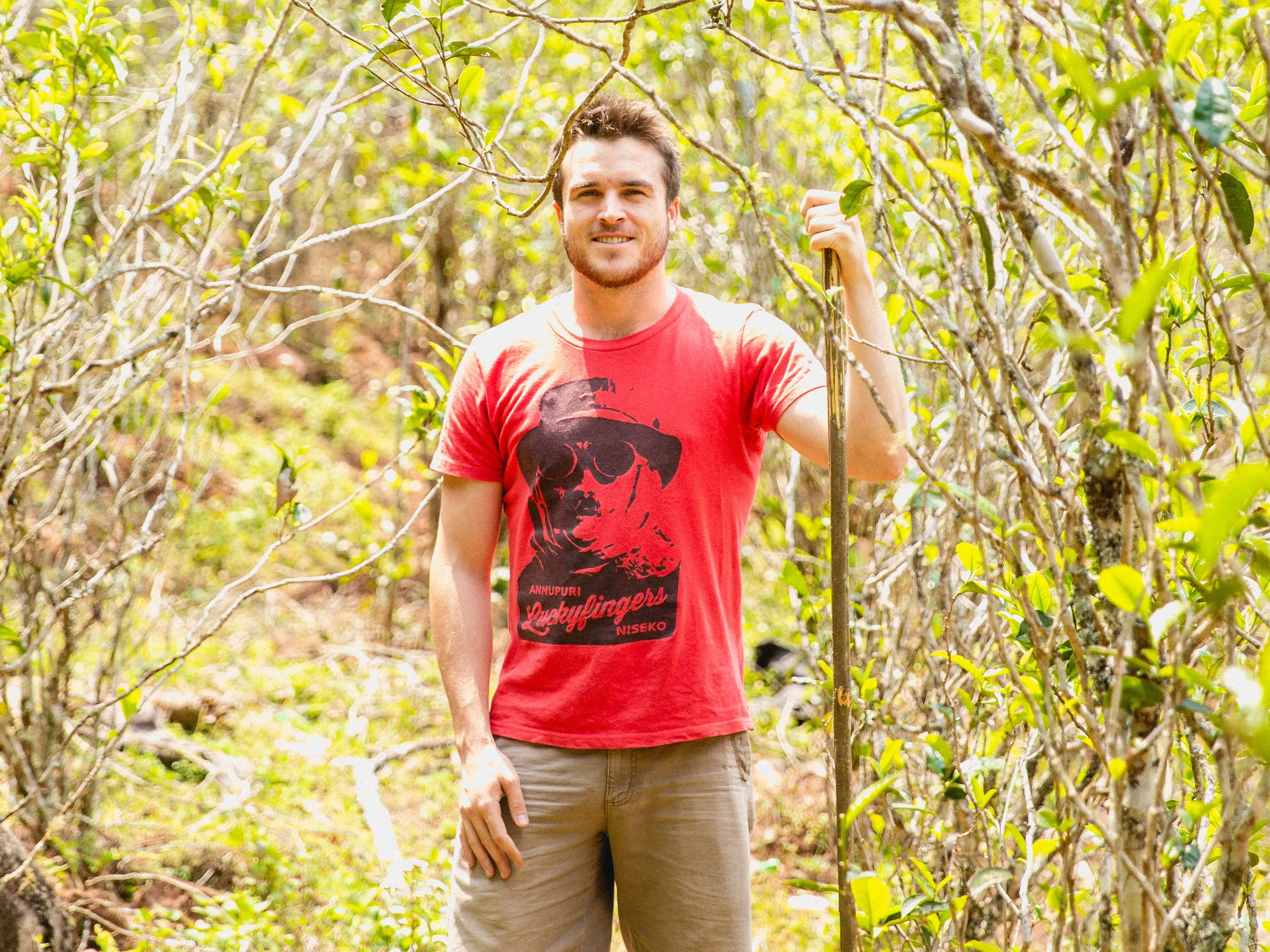 Man in a red shirt stading in a tea garden in Yunnan