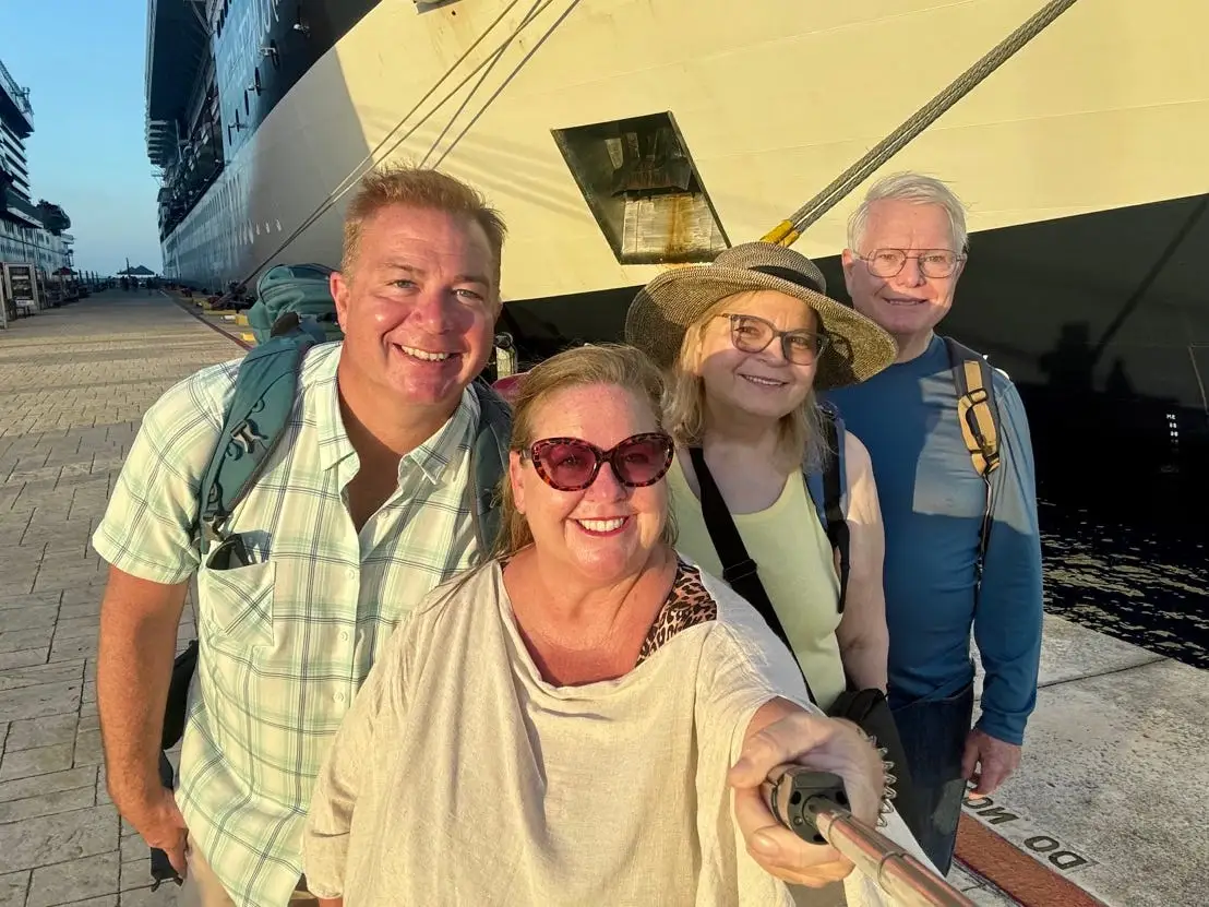 Author, husband, and in laws smiling for selfie in front of cruise ship