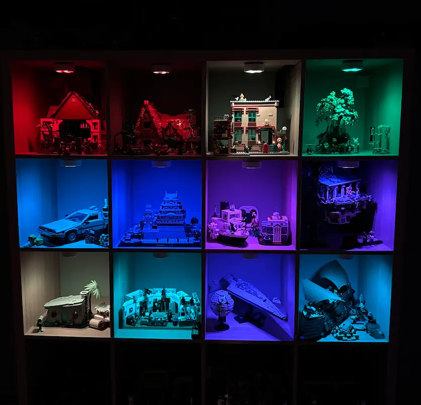 A bookcase with 12 lit up, ornate Lego sets