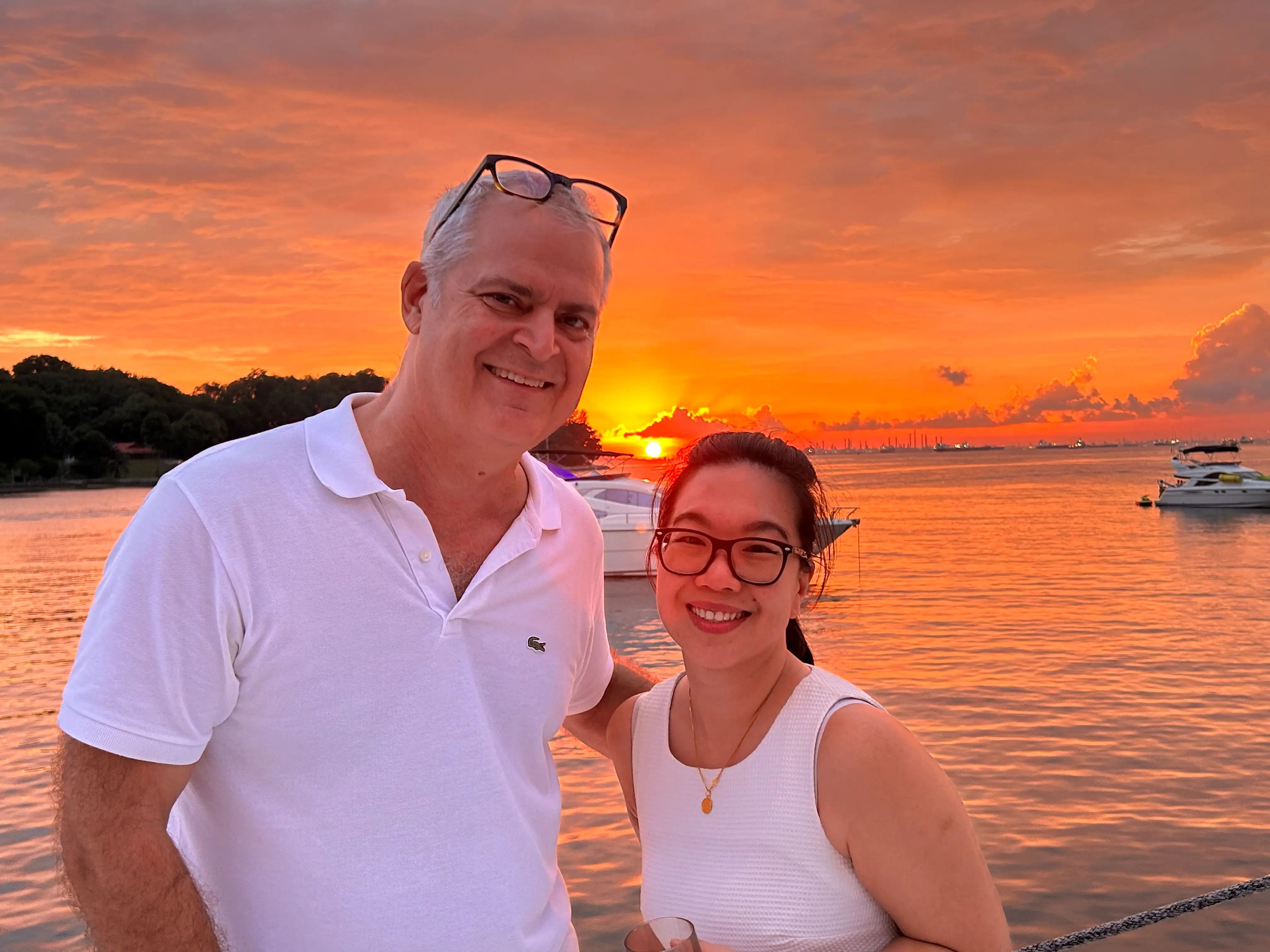 Kris LeBoutillier and his wife are posing near a sunset in Singapore.