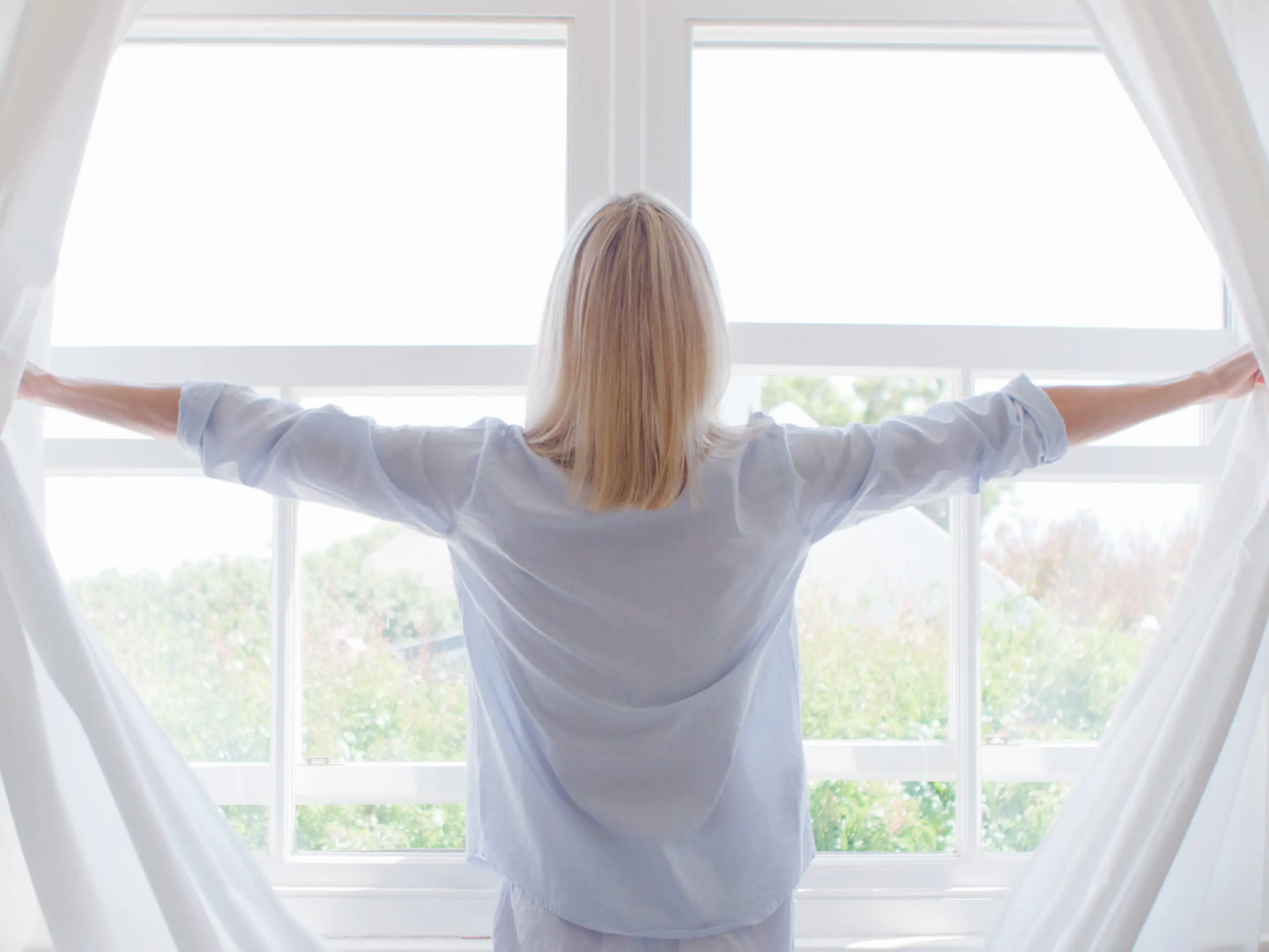 Woman opening curtains.