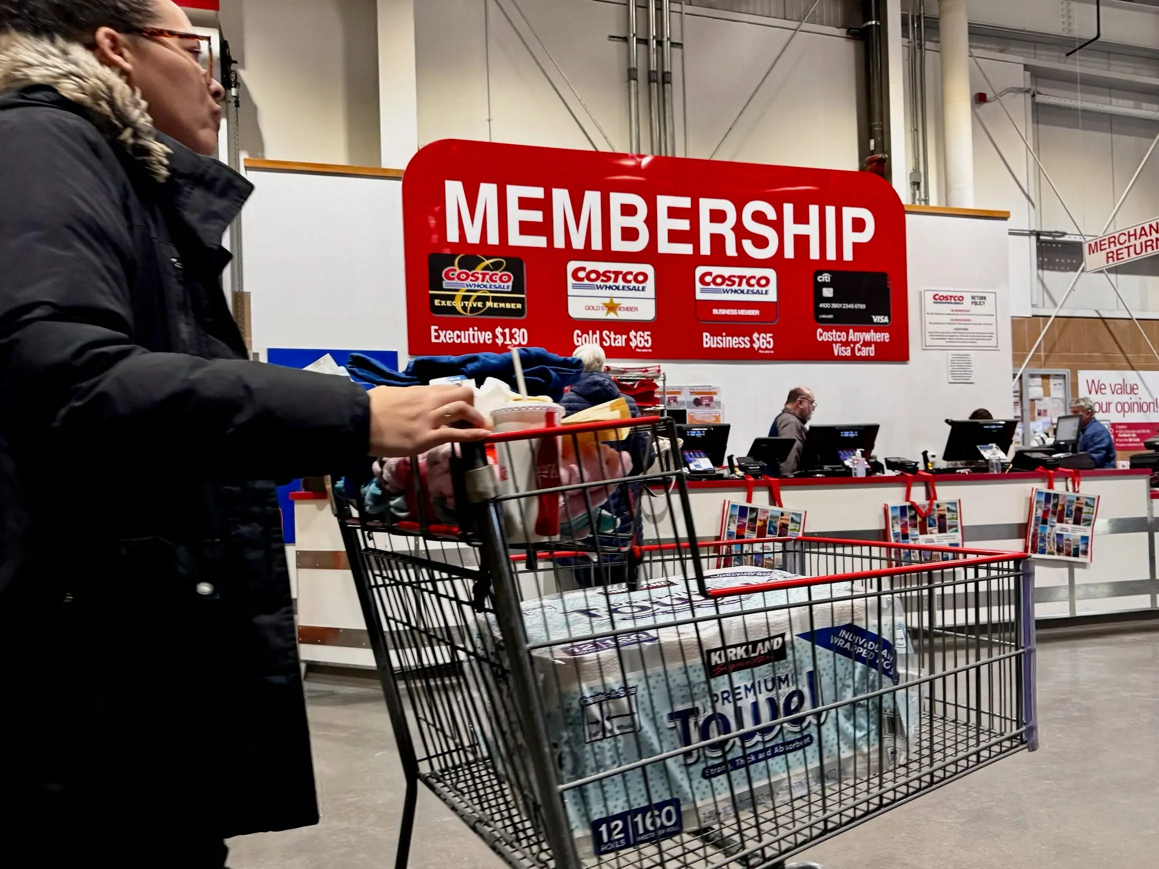 A Costco shopper pushes a cart past the membership desk.