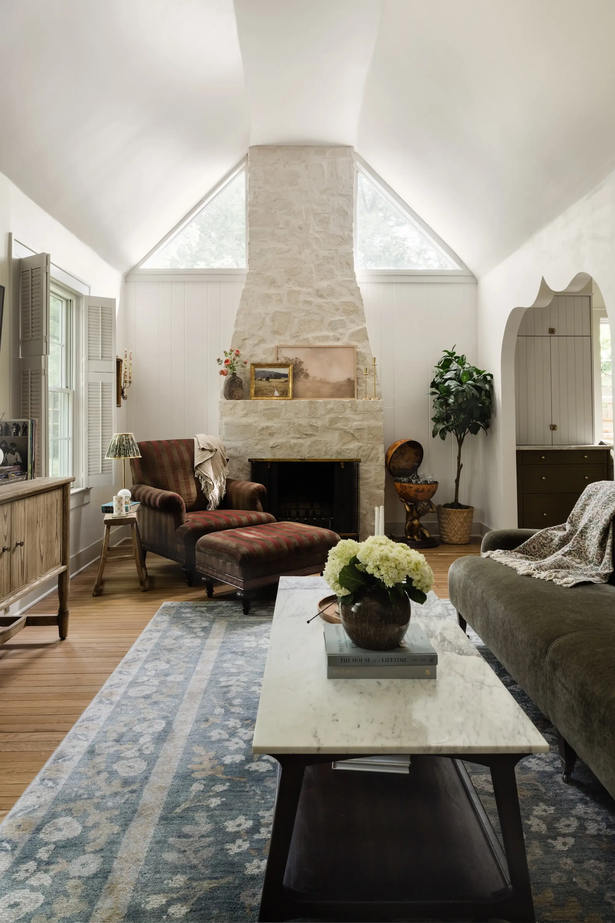 A living room with a curved, stone fireplace.