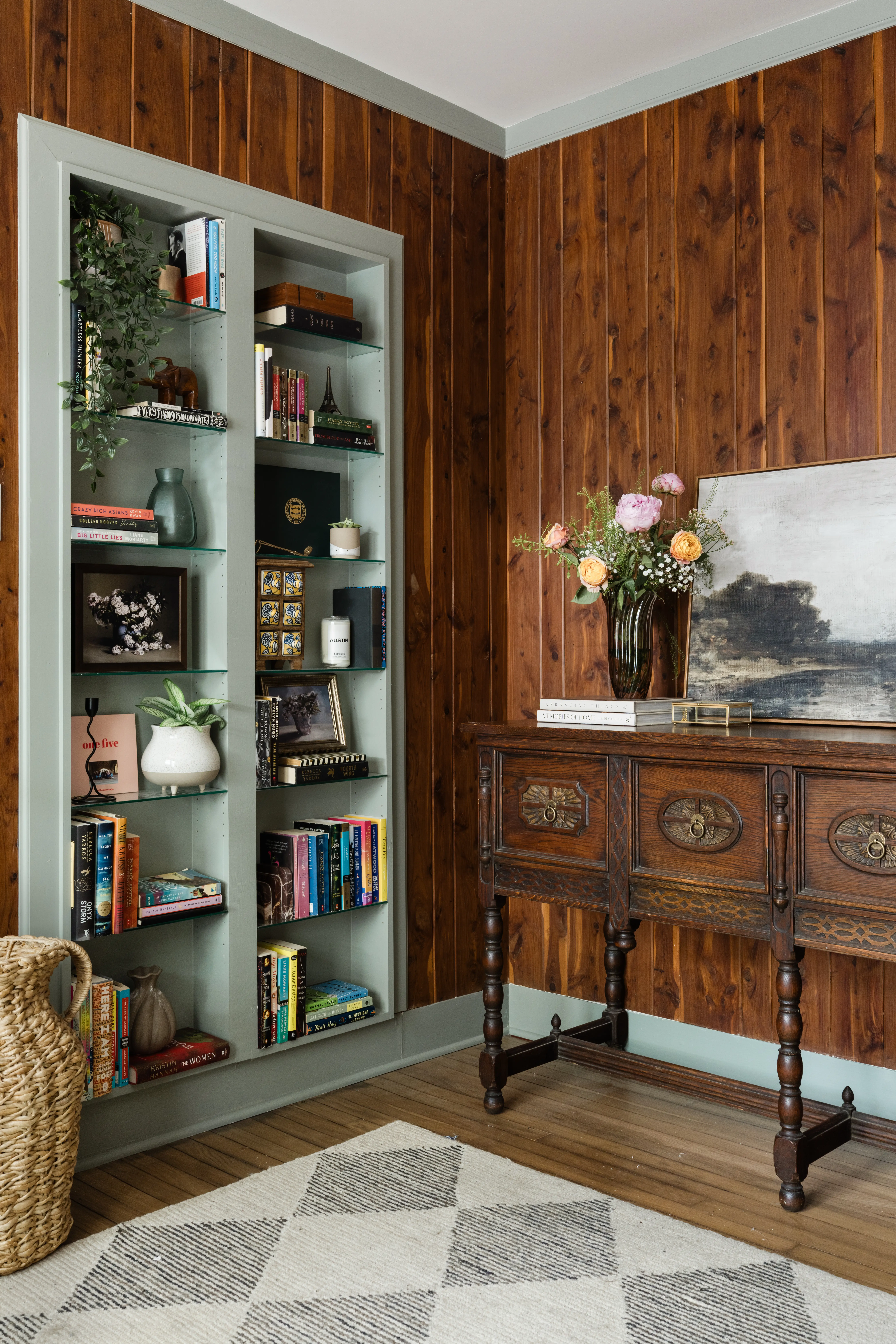 A room with built-in green shelves and a wooden side table.