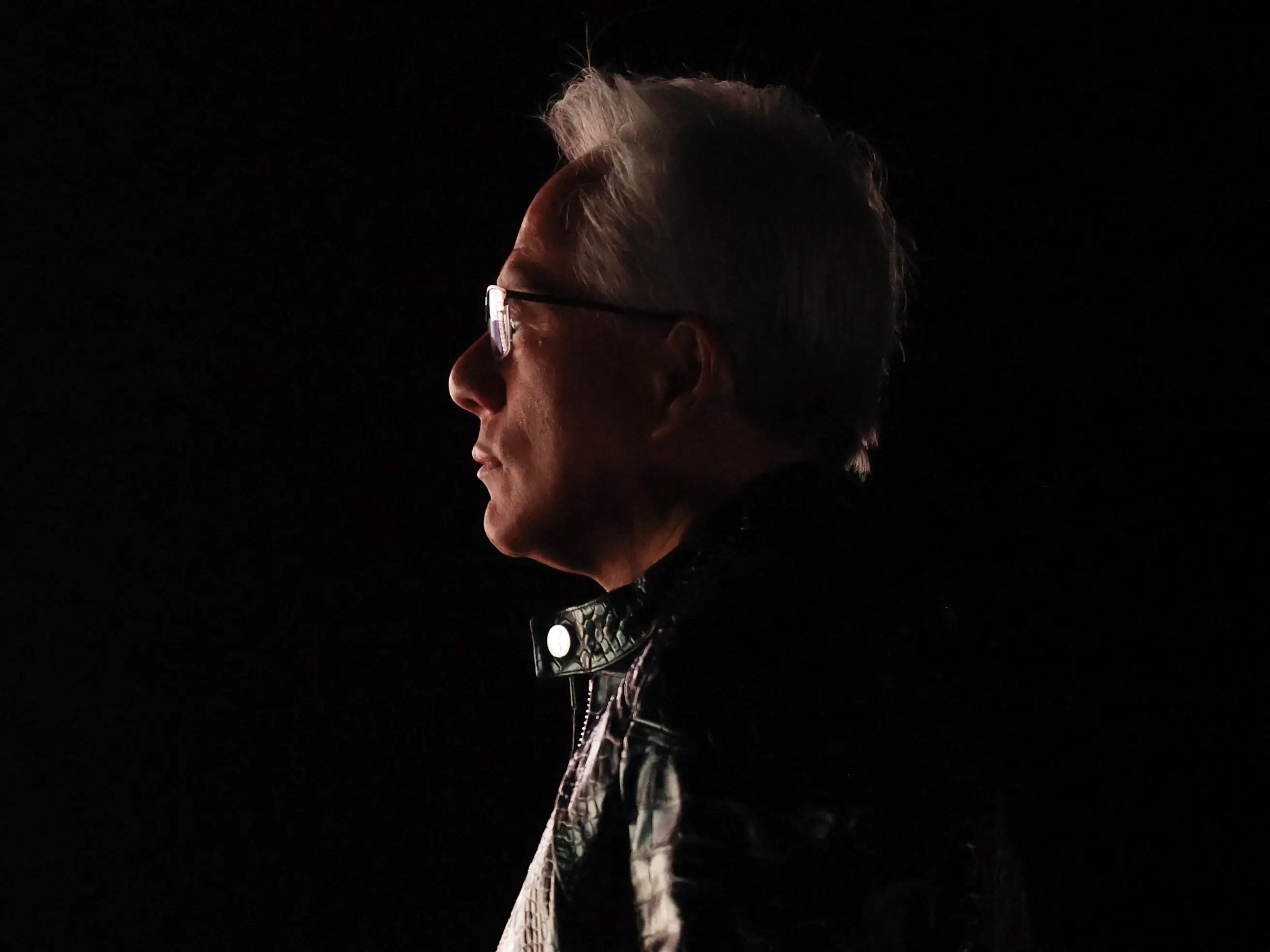 Jensen Huang in profile in shadows.