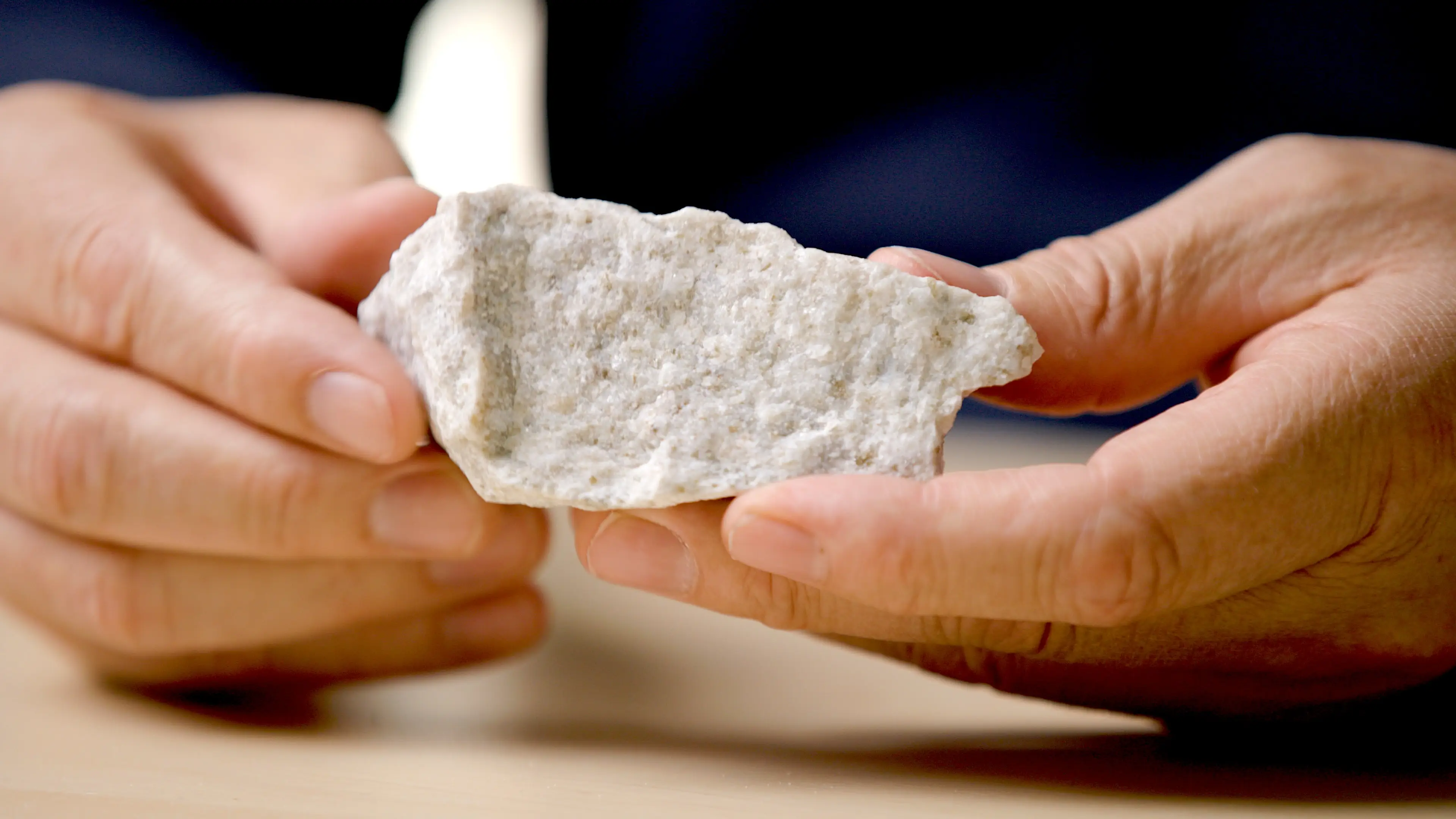 Close up of a person holding a white rock that is anorthosite.