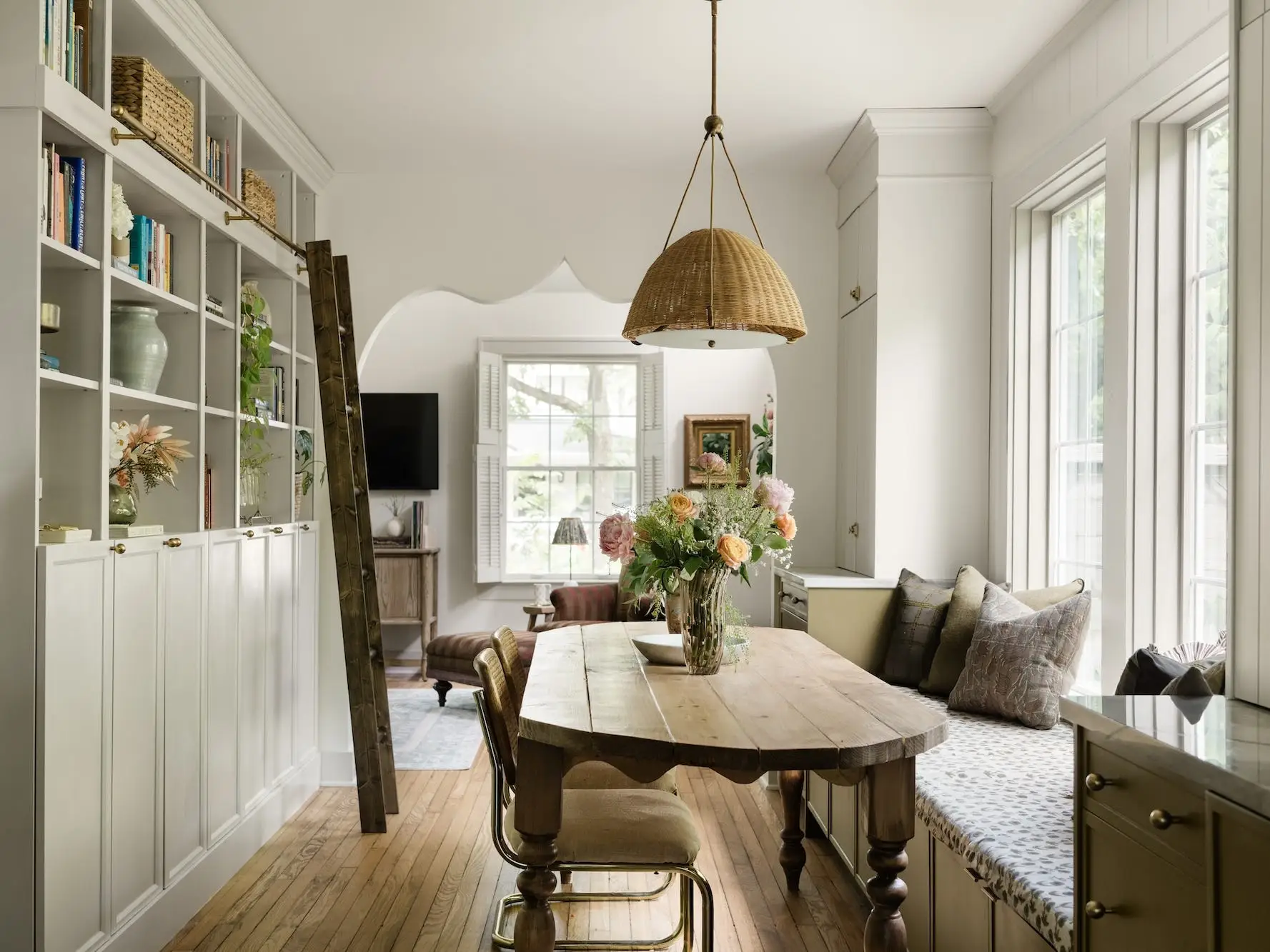 A dining area with a table, bench seating, and a bookshelf.