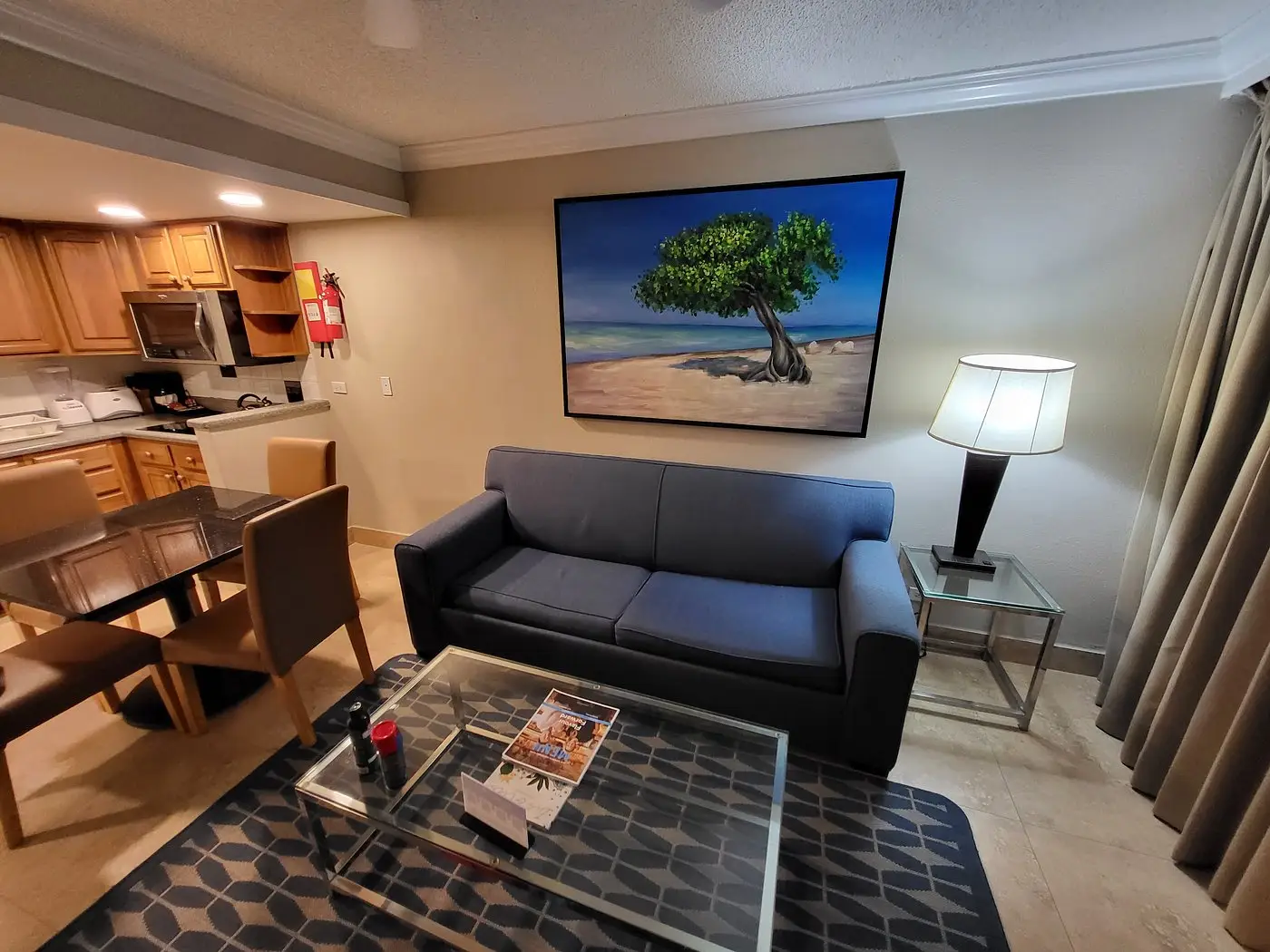 Living area with small couch, framed artwork, side table and lamp