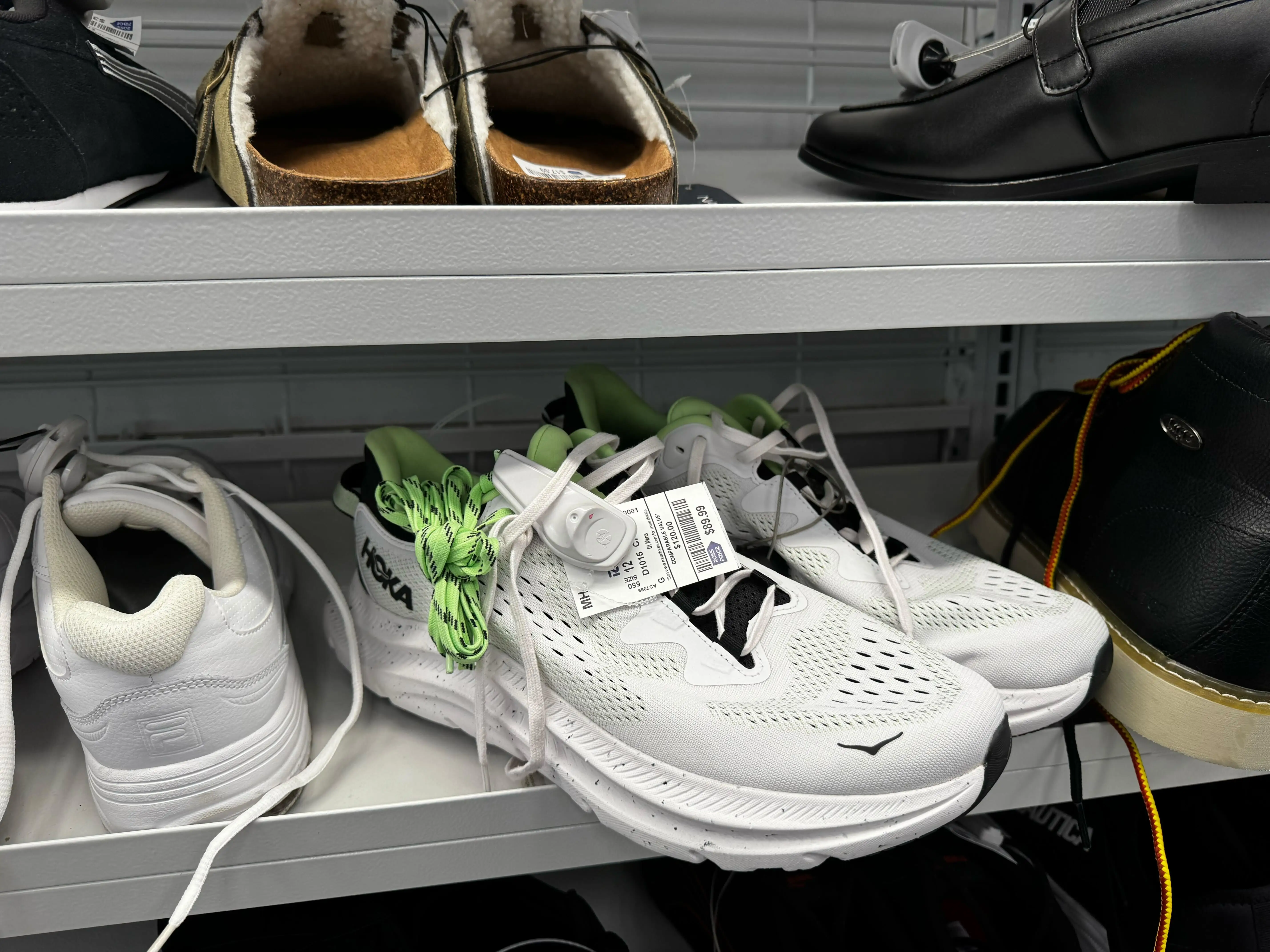 A pair of white men's Hoka athletic shoes sit on a shelf at a Ross store in Wisconsin.