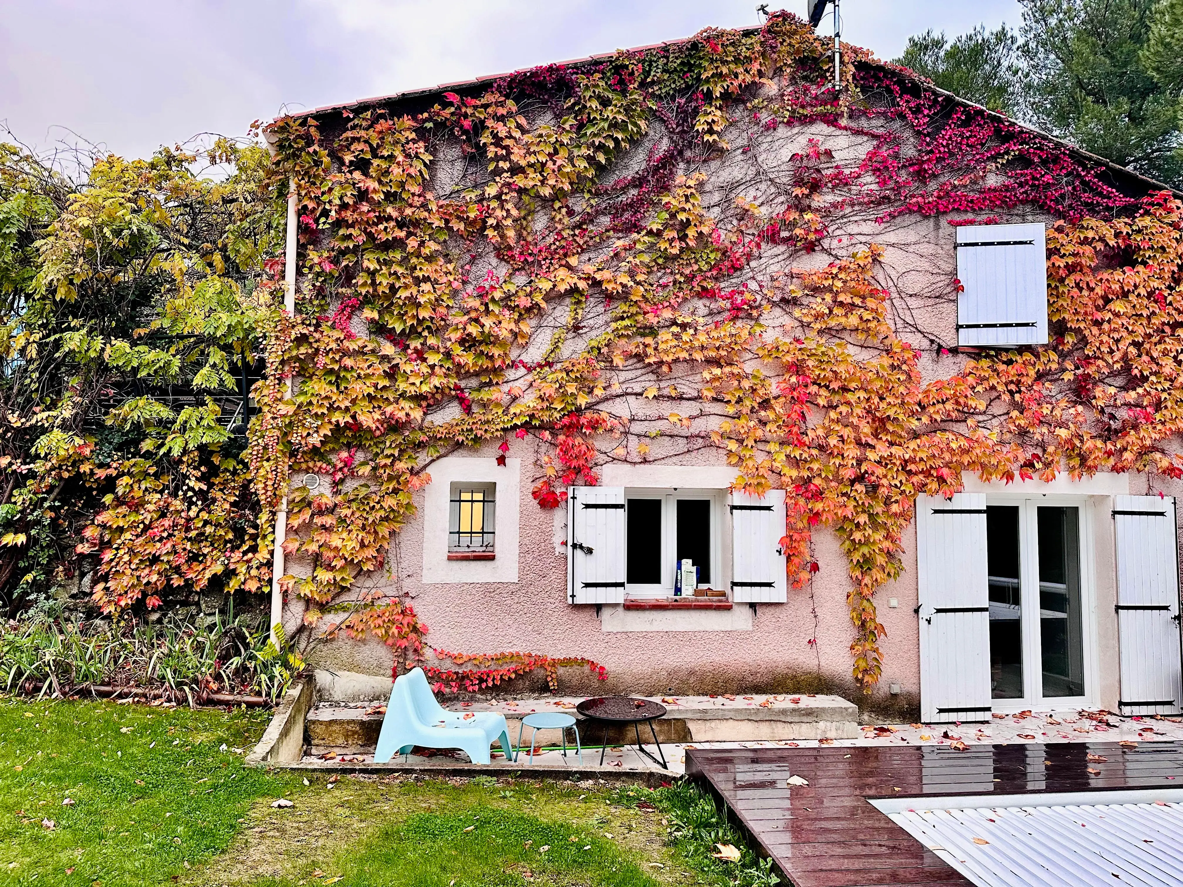 A pink home covered in leaves in France.