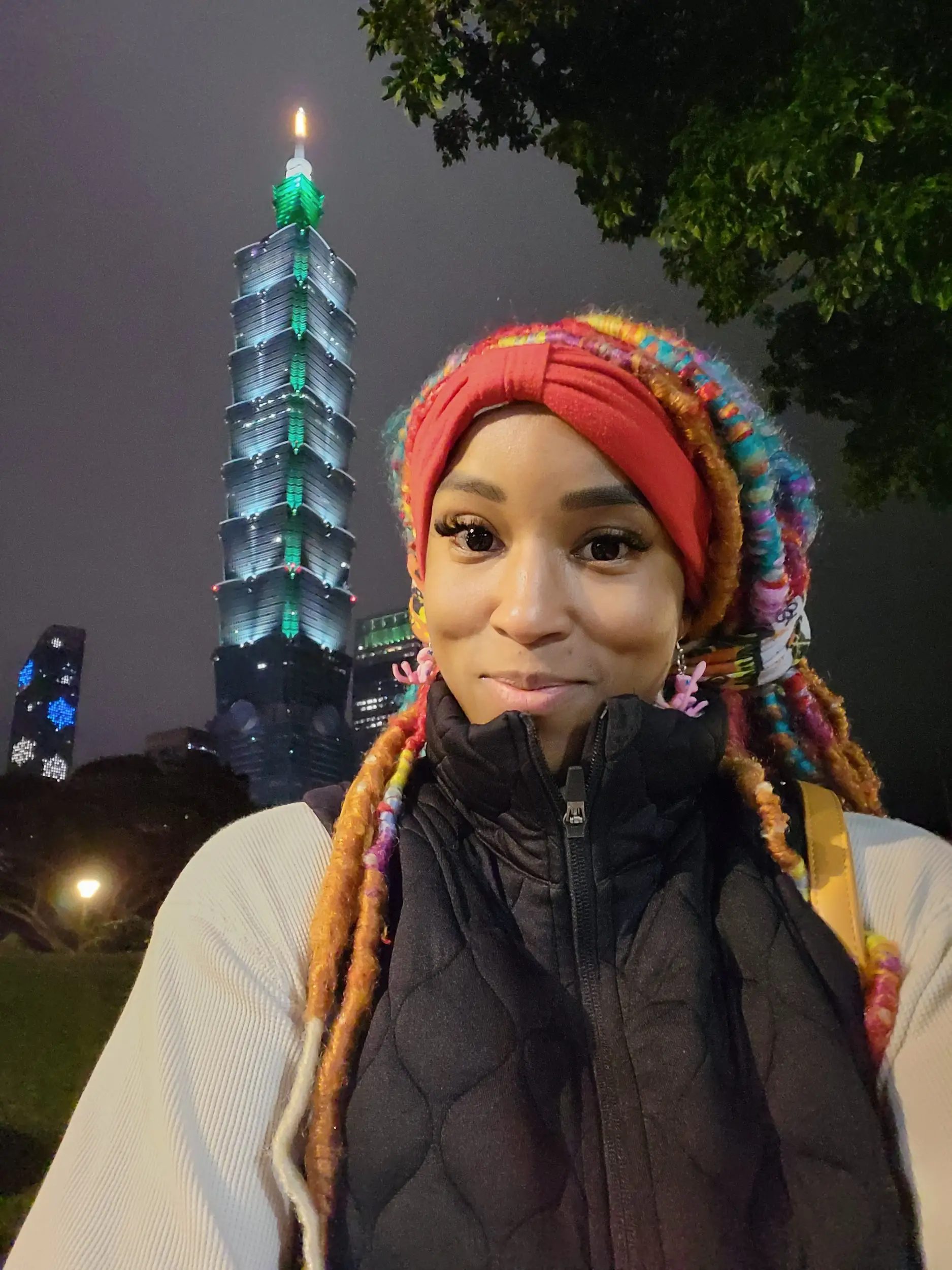 A woman taking a selfie with Taipei 101 in the background.