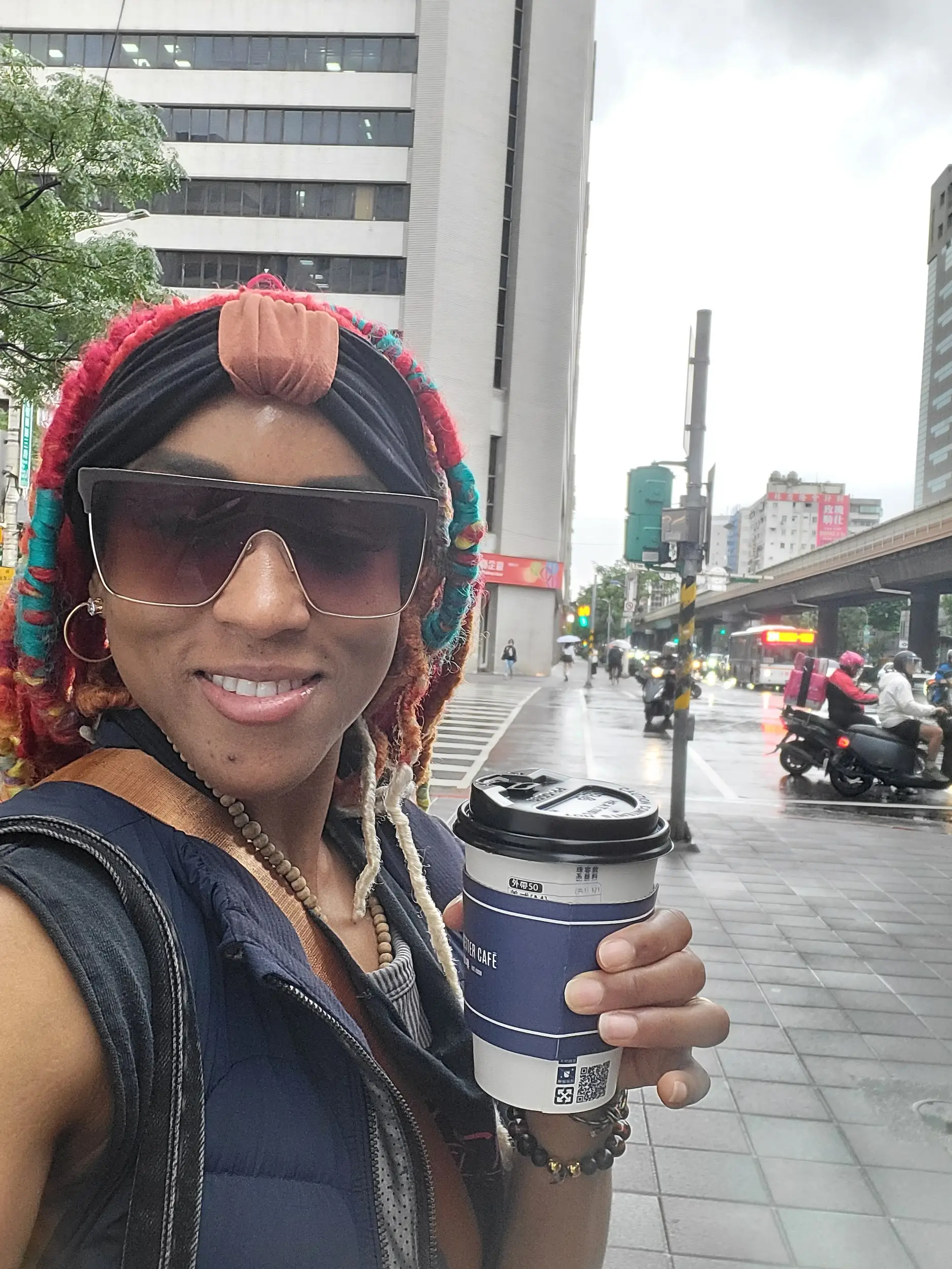 A woman taking a selfie with a cup of coffee in her hand.