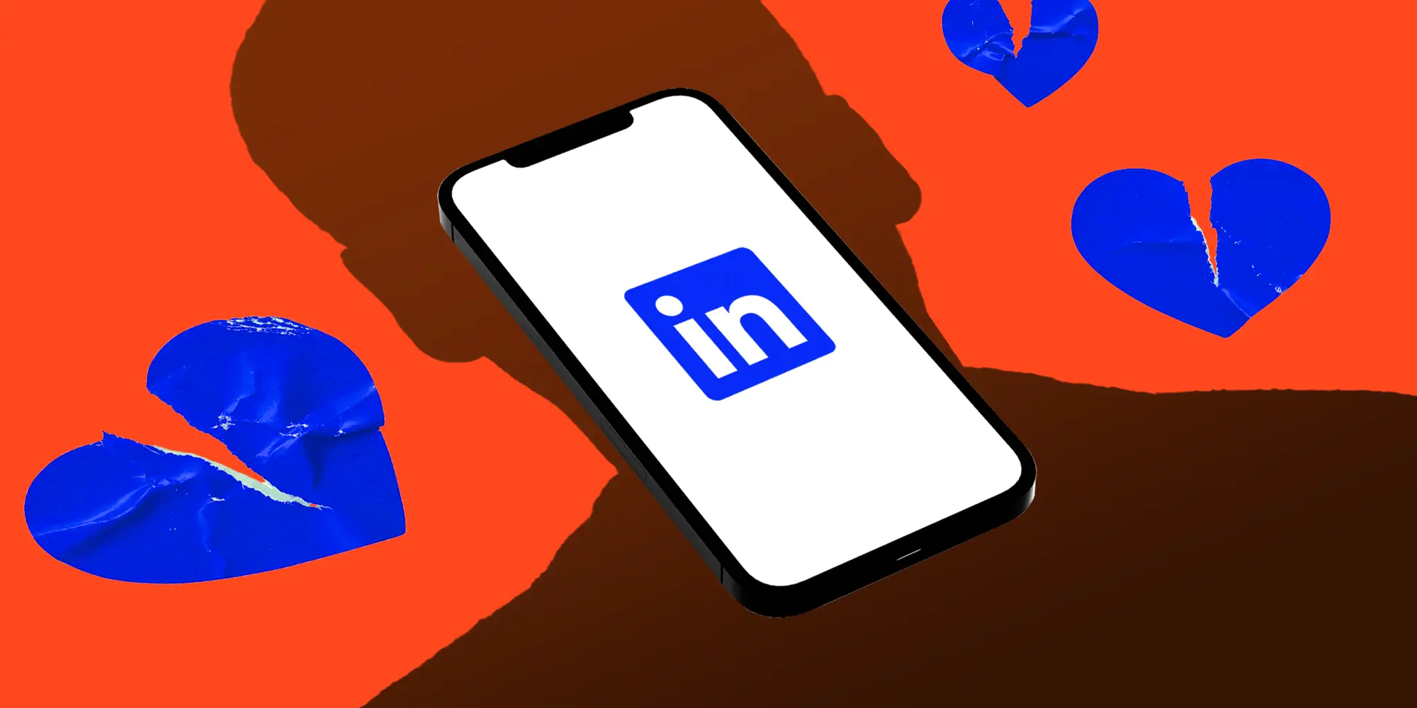 A phone displaying the Linkedin logo as a human shadow casts over it with broken paper hearts