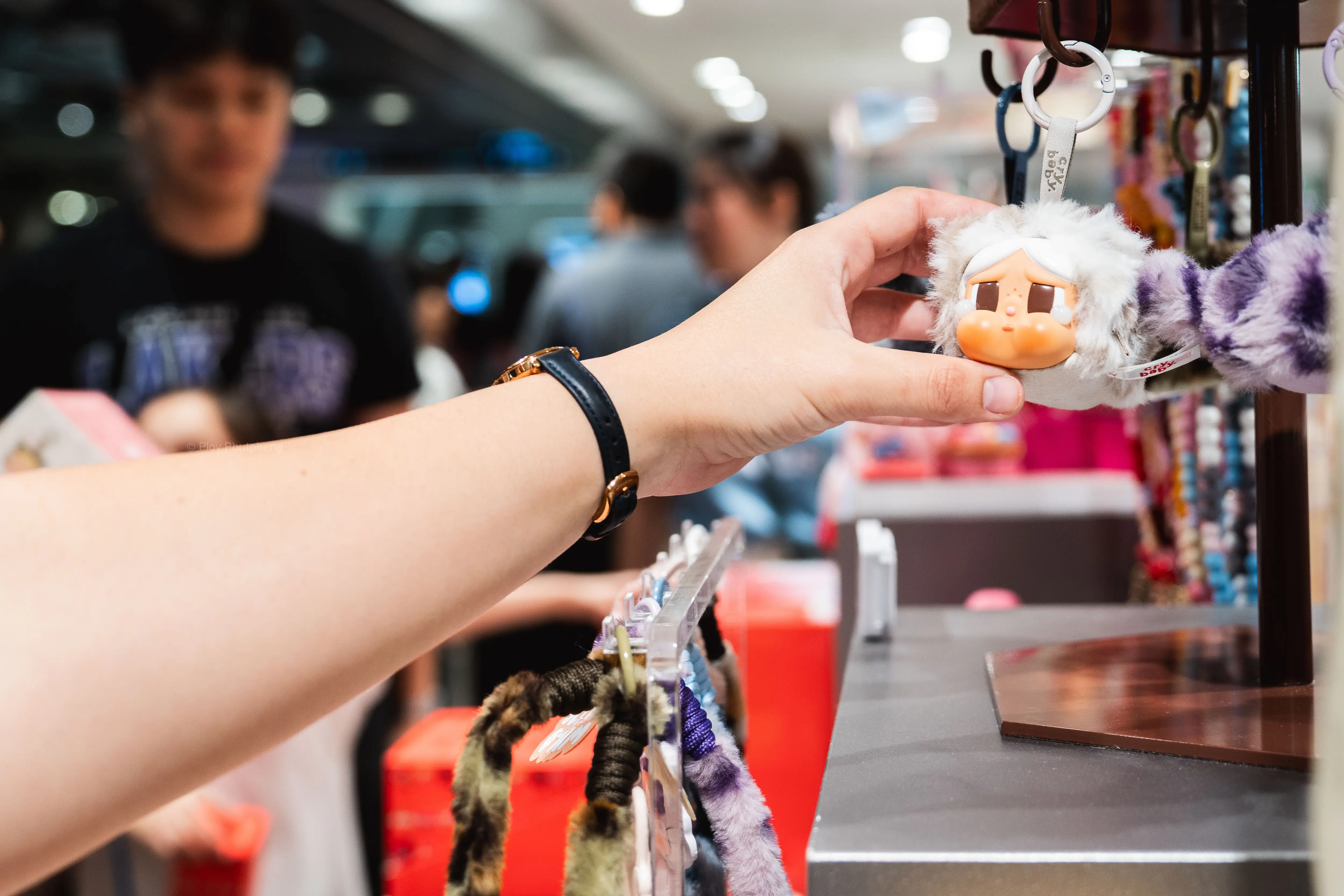 A hand reaches for a collectible keychain.