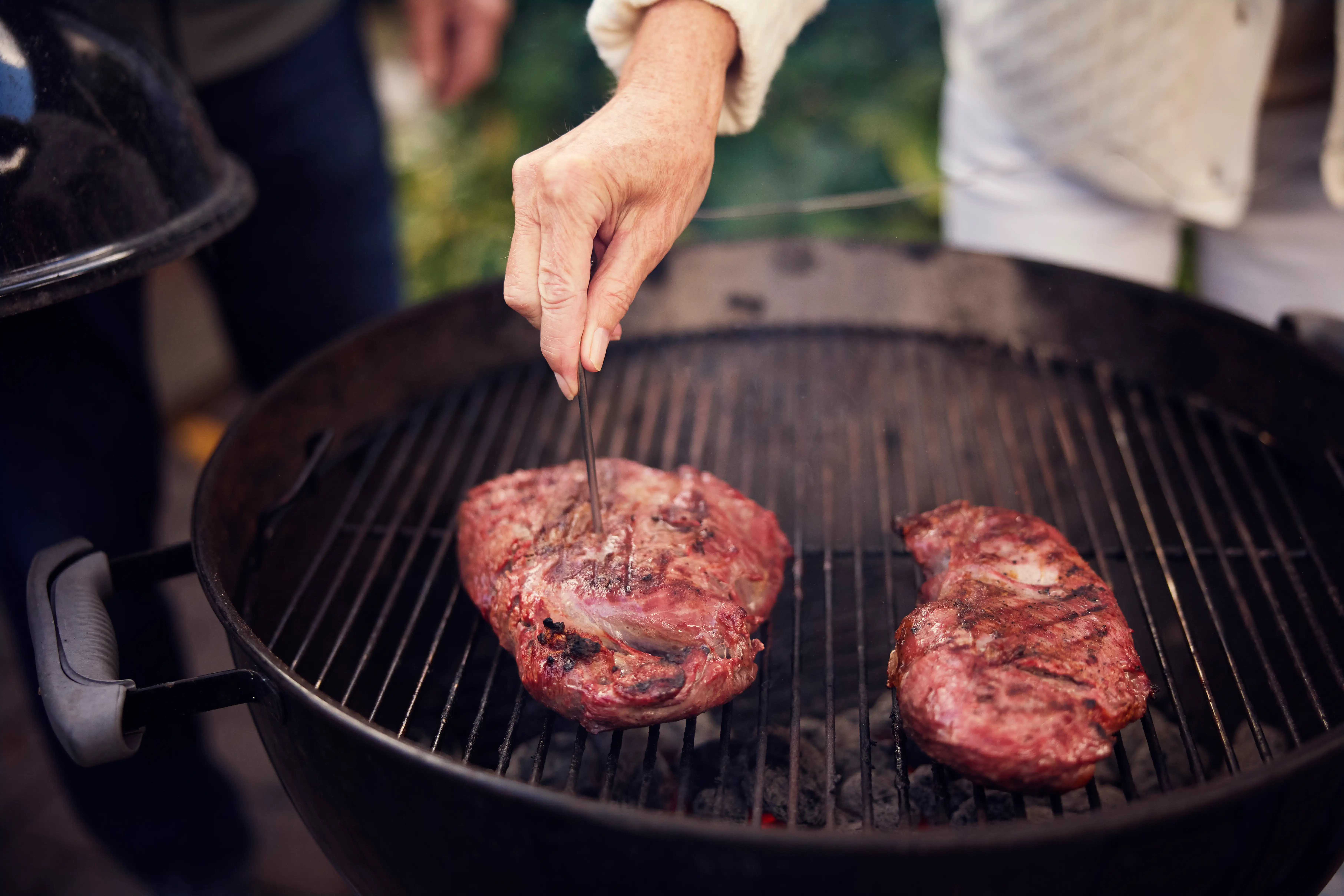 Red meat cooking on an outdoor grill.