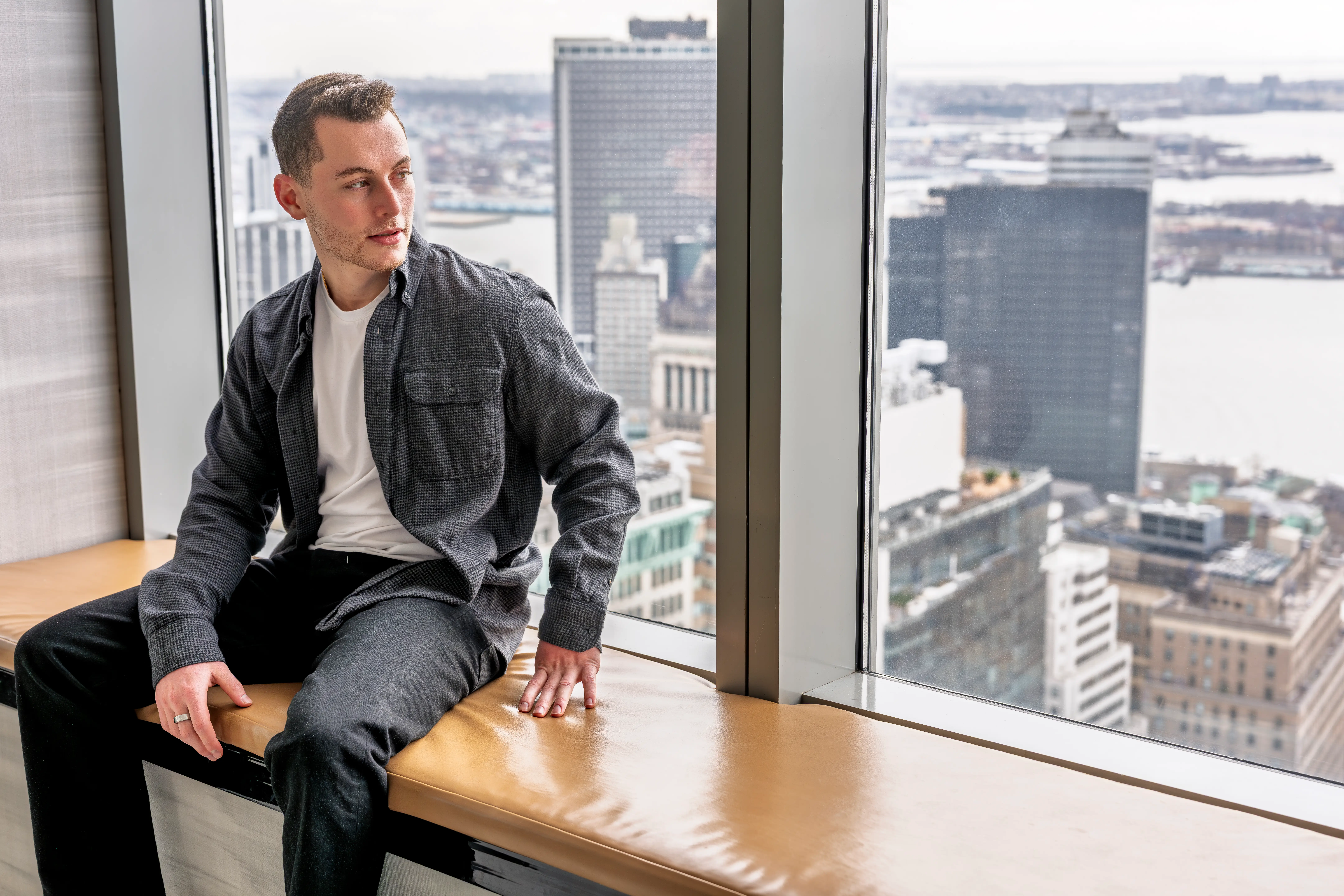 Oscar Rachmansky sitting next to window with city in background.