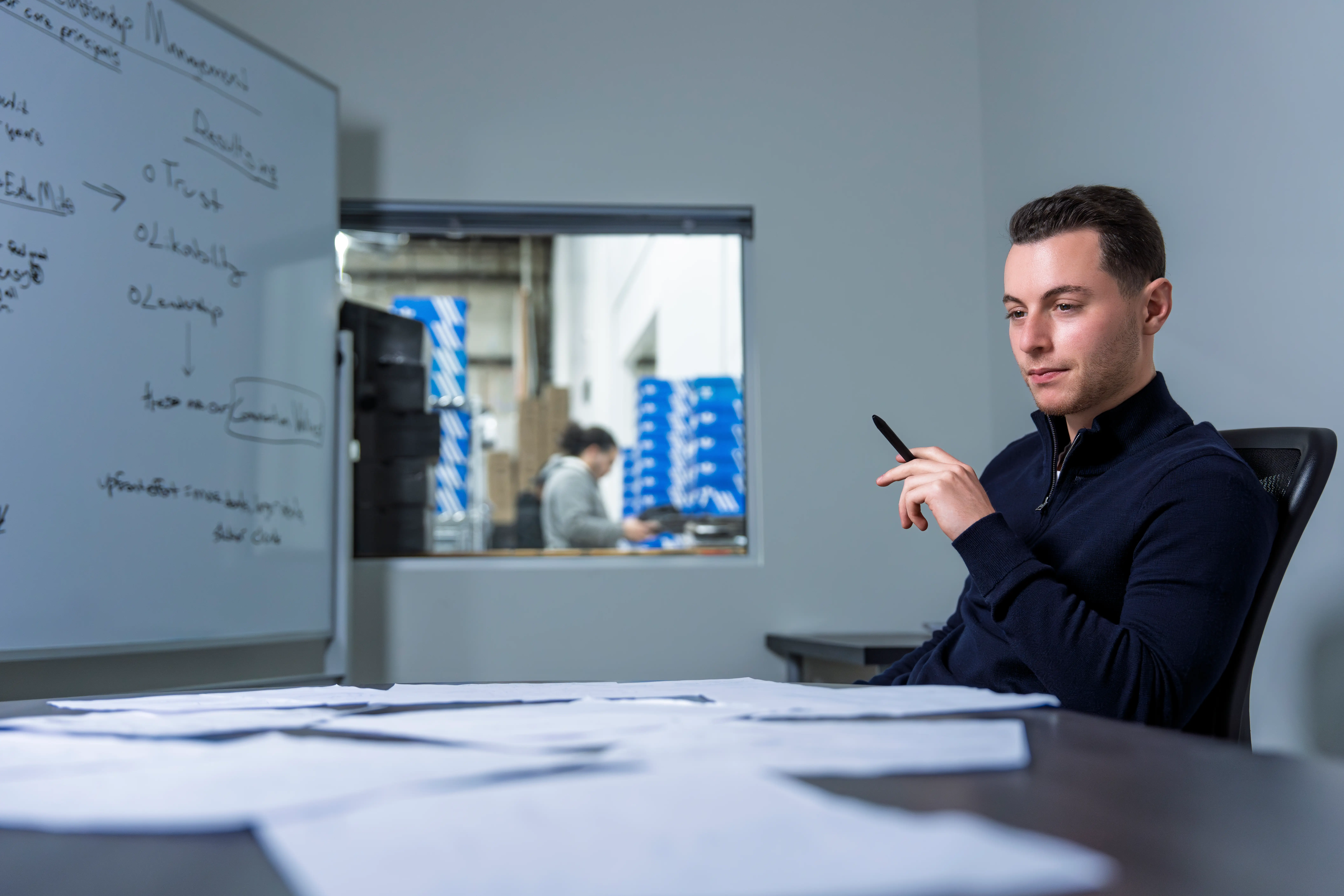 Oscar Rachmansky in office at OS Group facility at desk with paper all across it.
