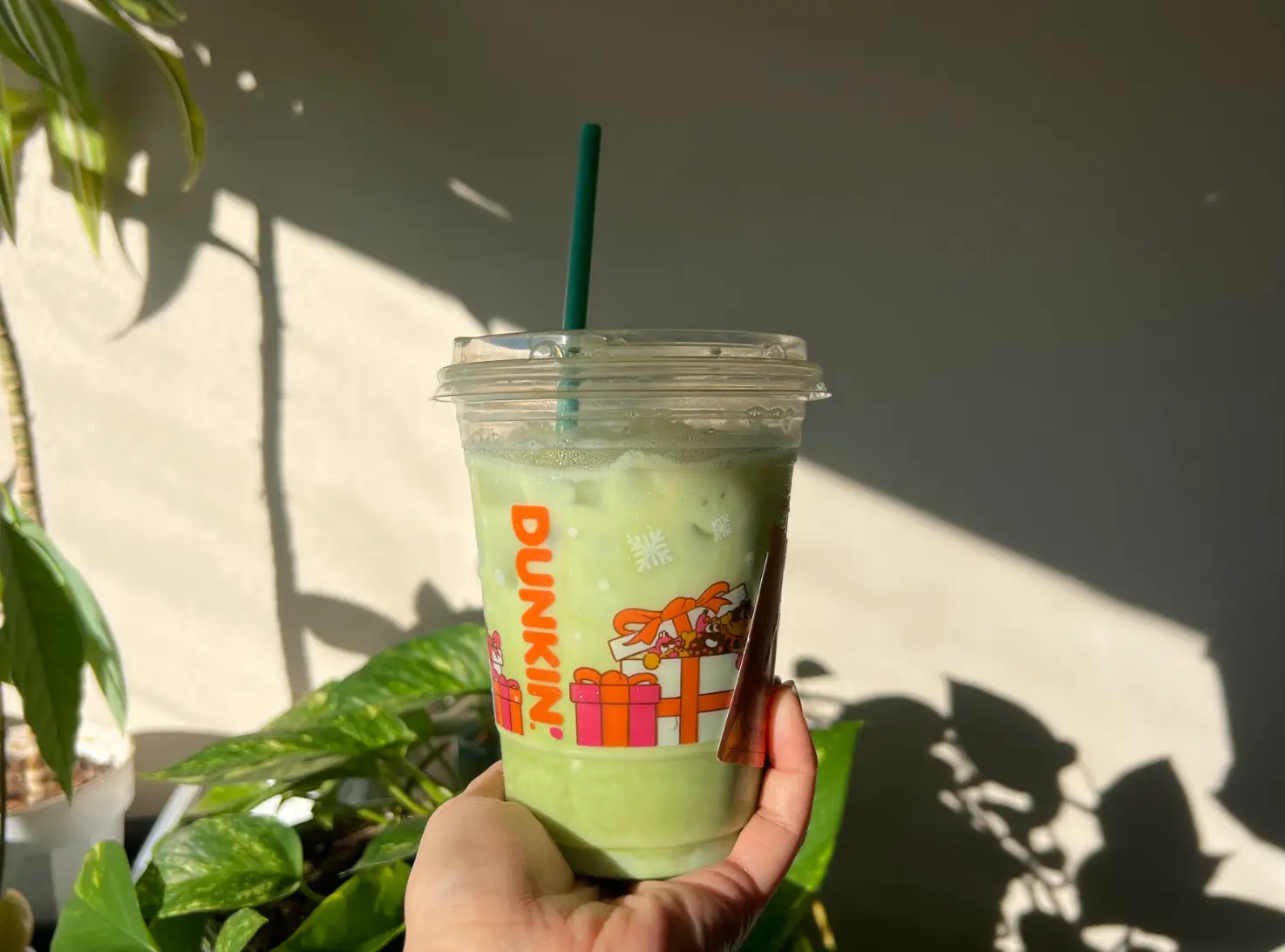 The writer holding an iced almond matcha with protein from Dunkin'.