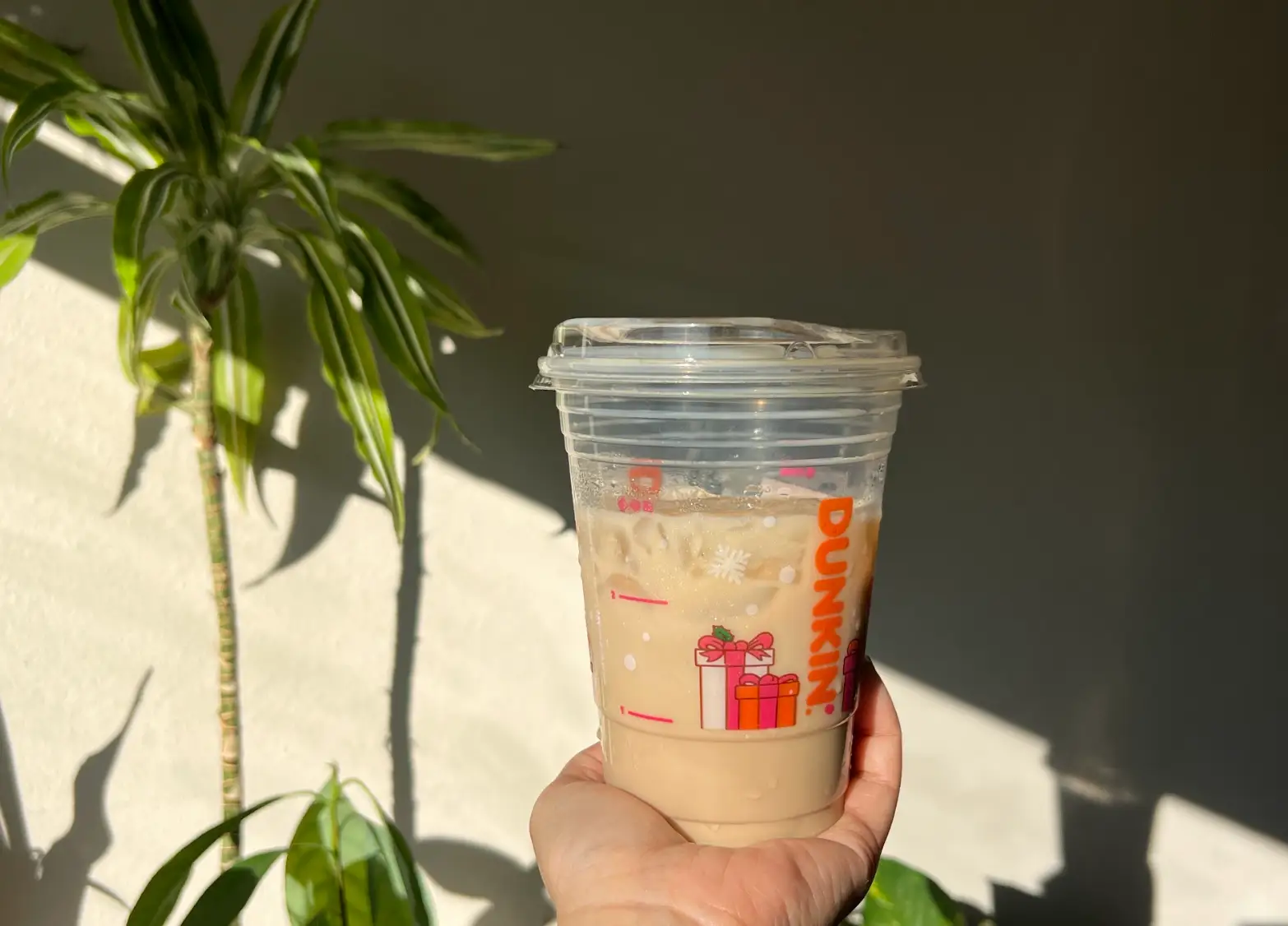 The writer holding an iced chocolate-caramel protein latte from Dunkin'.