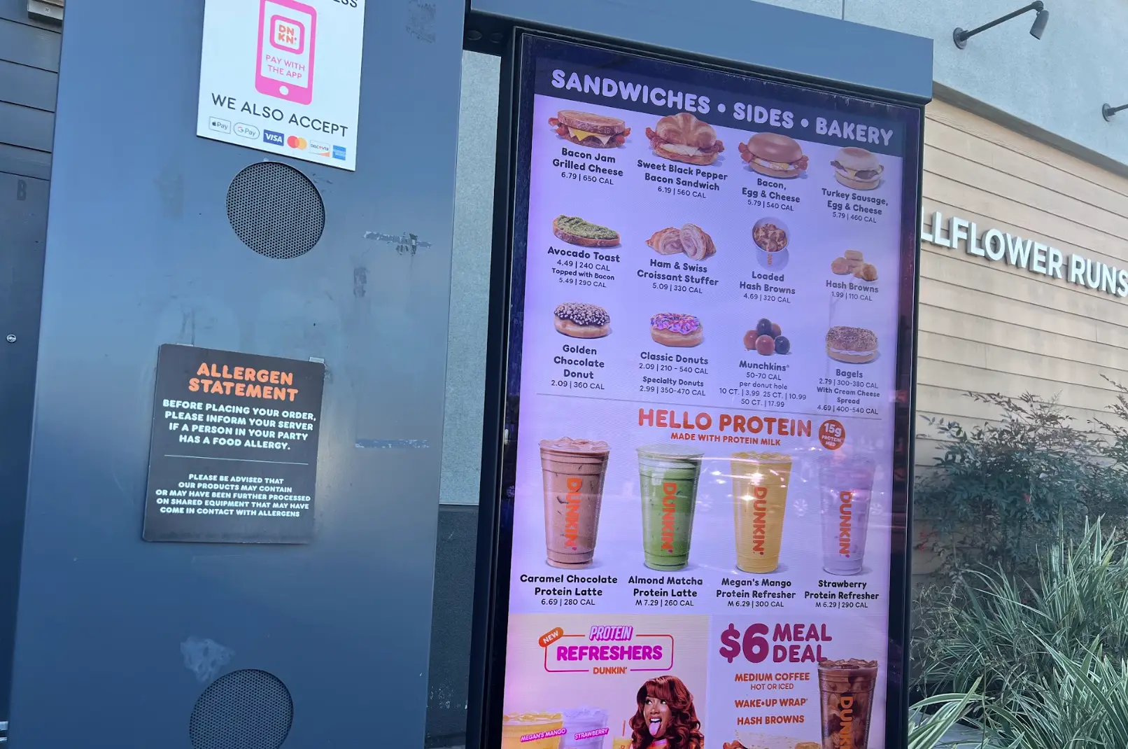 An exterior of a Dunkin' drive-thru, with a menu.