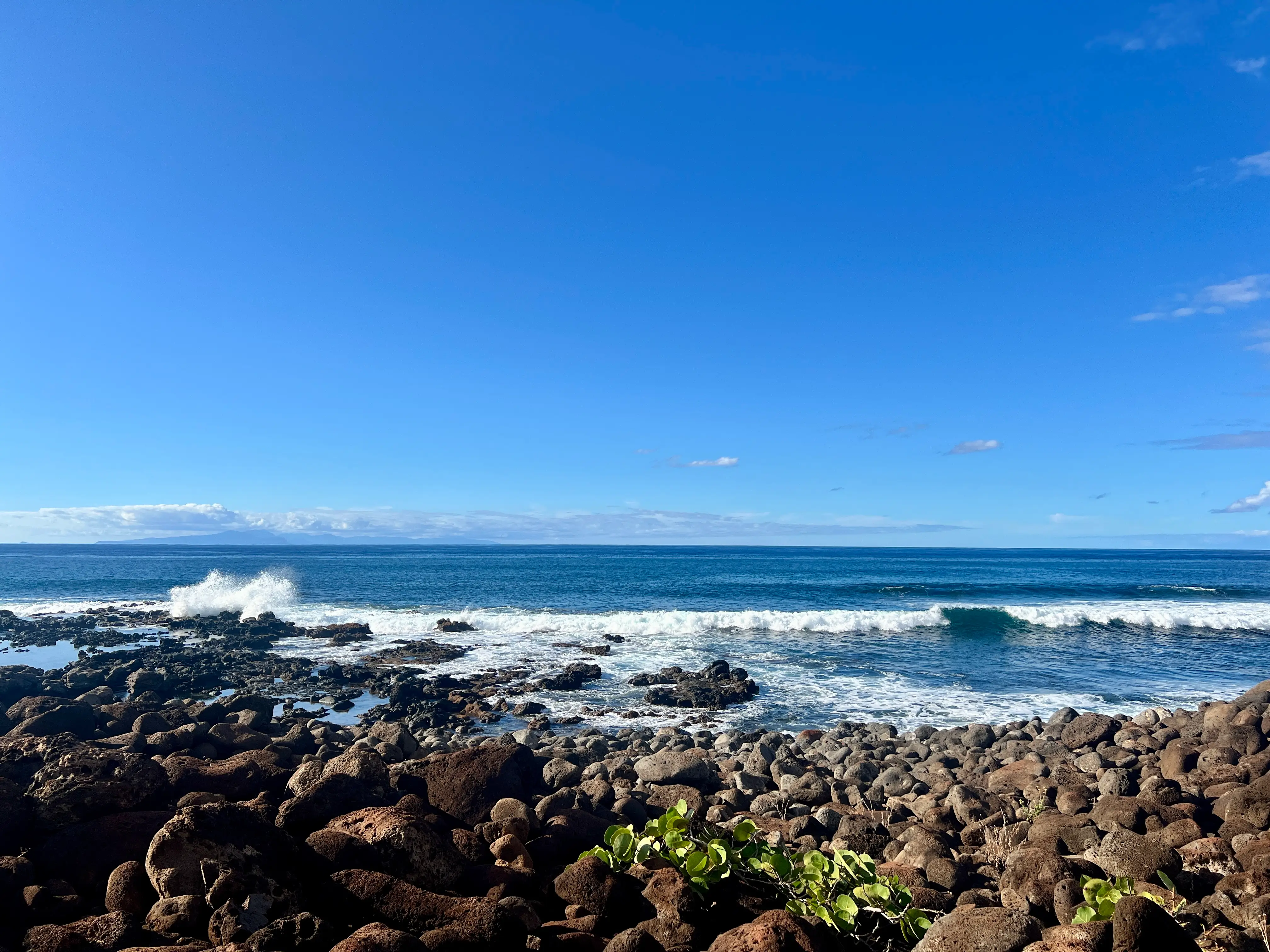 Stones along shorline with waves behind them in Hawaii