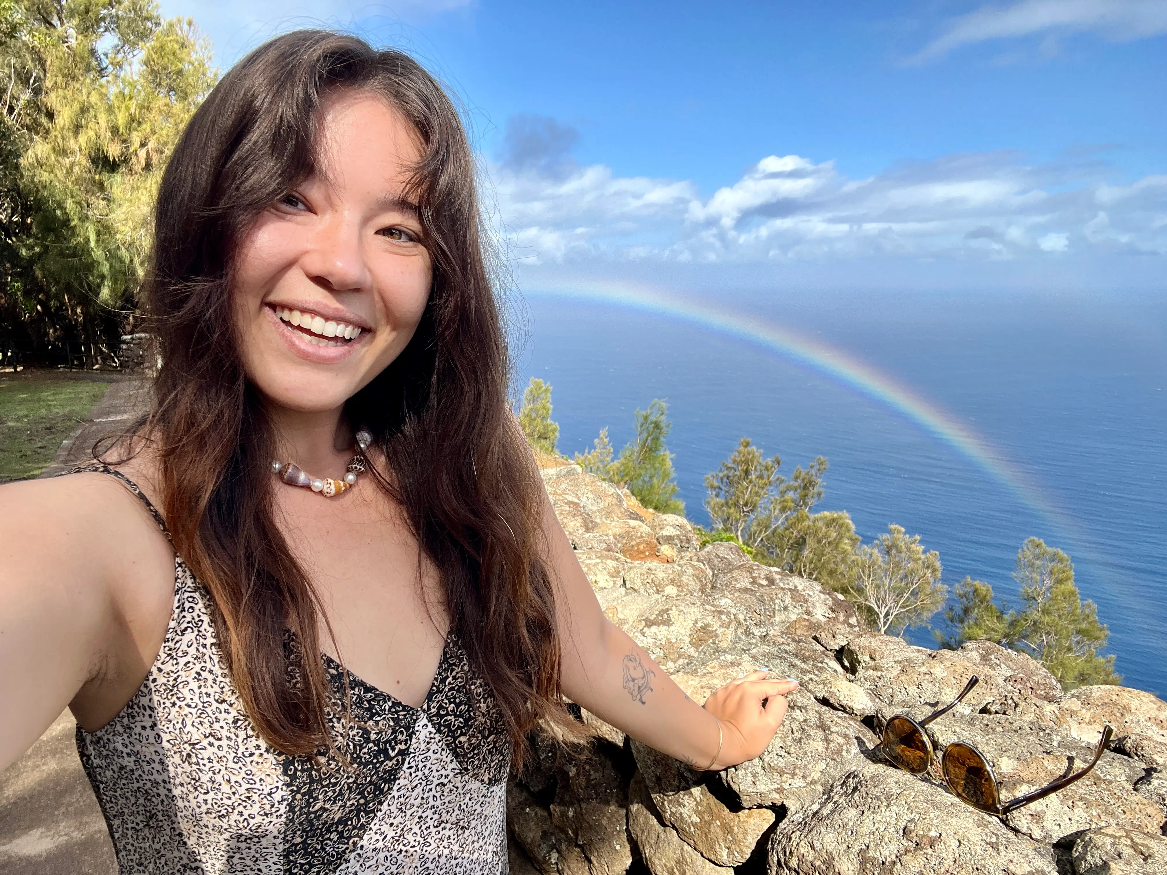 Author Ashley Probst smiling with rainbow and blue waters behind her