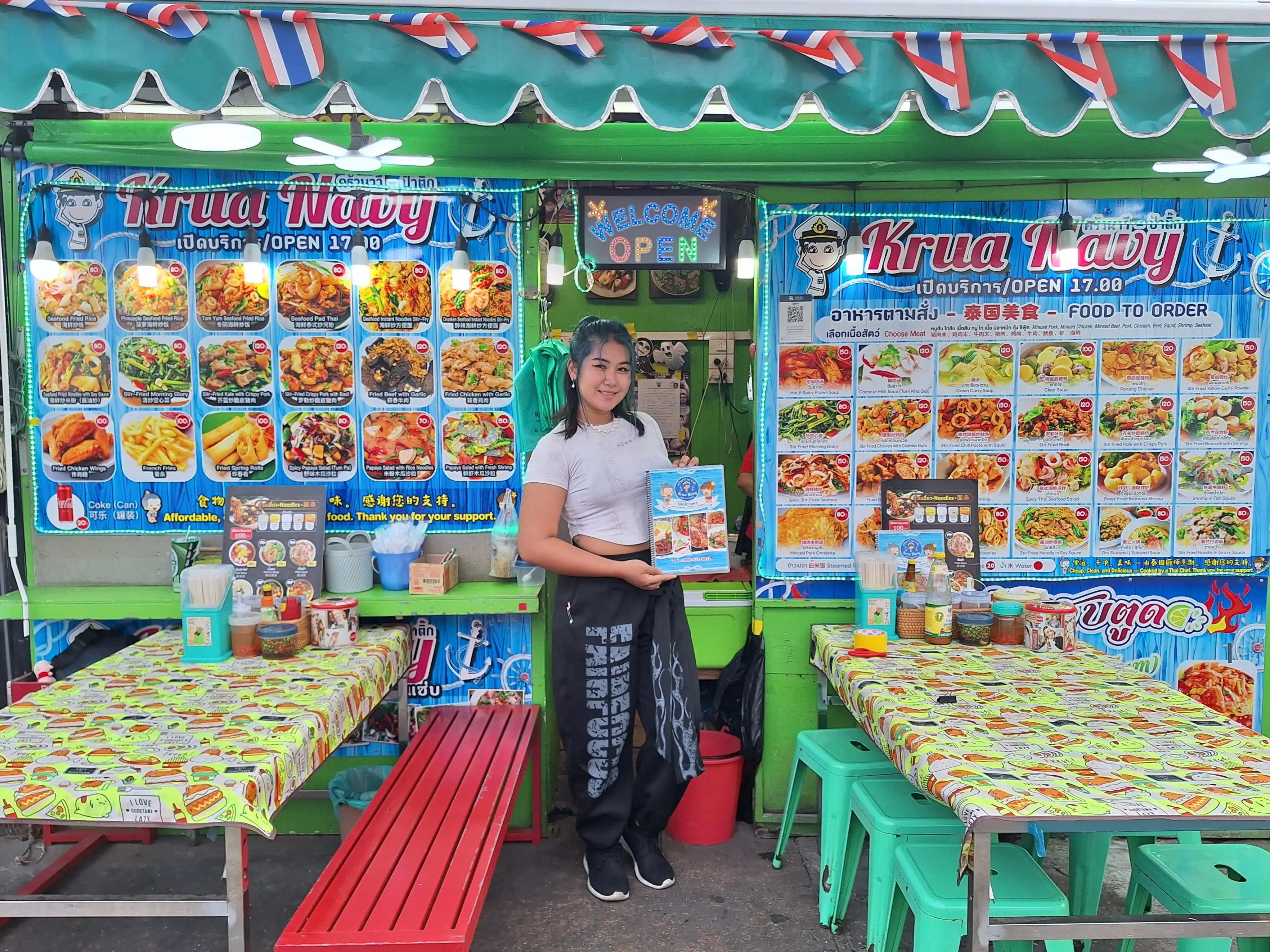 A woman showing the menu at a Thai street food restaurant.