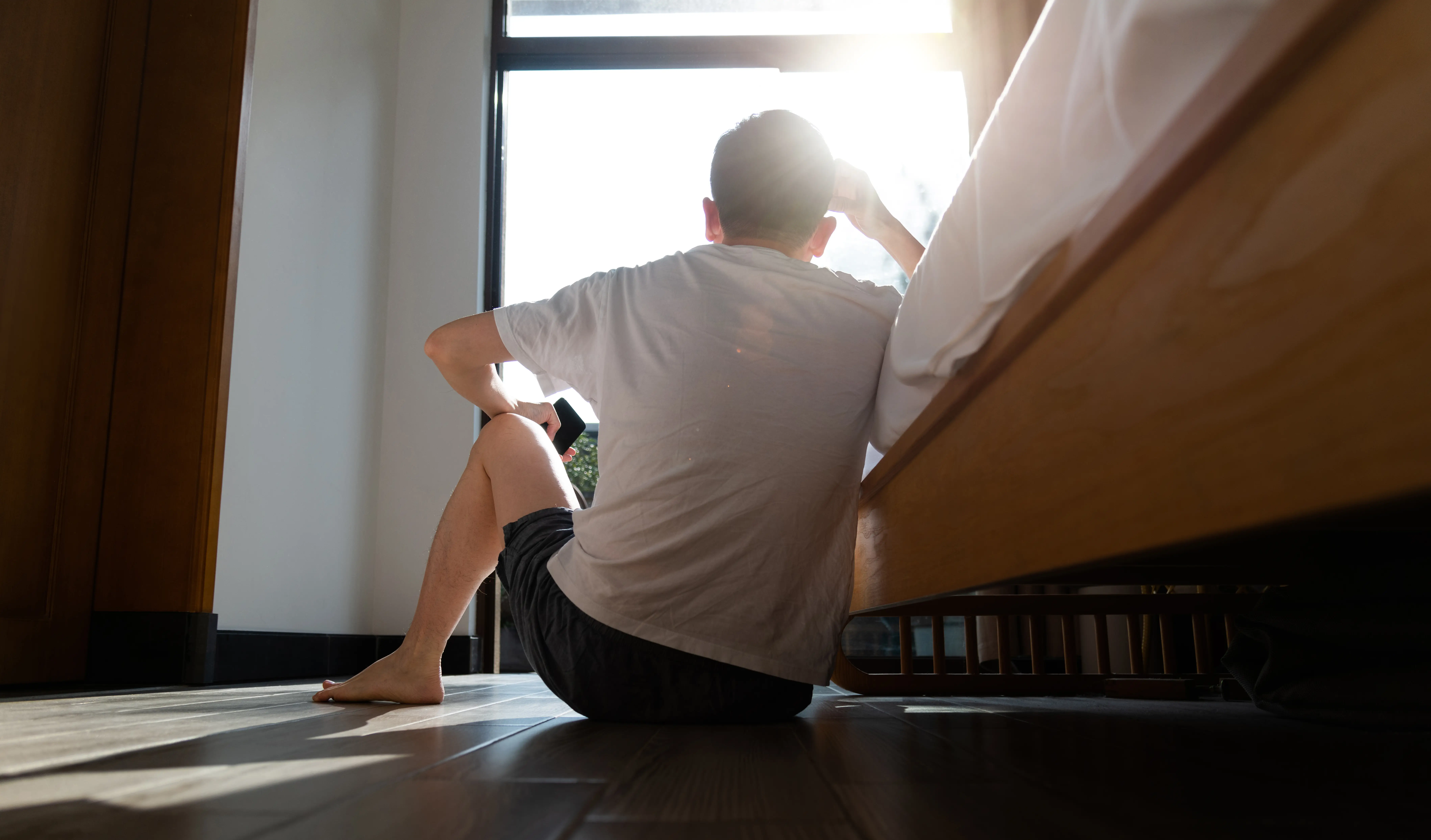 a young man sitting beside a bed