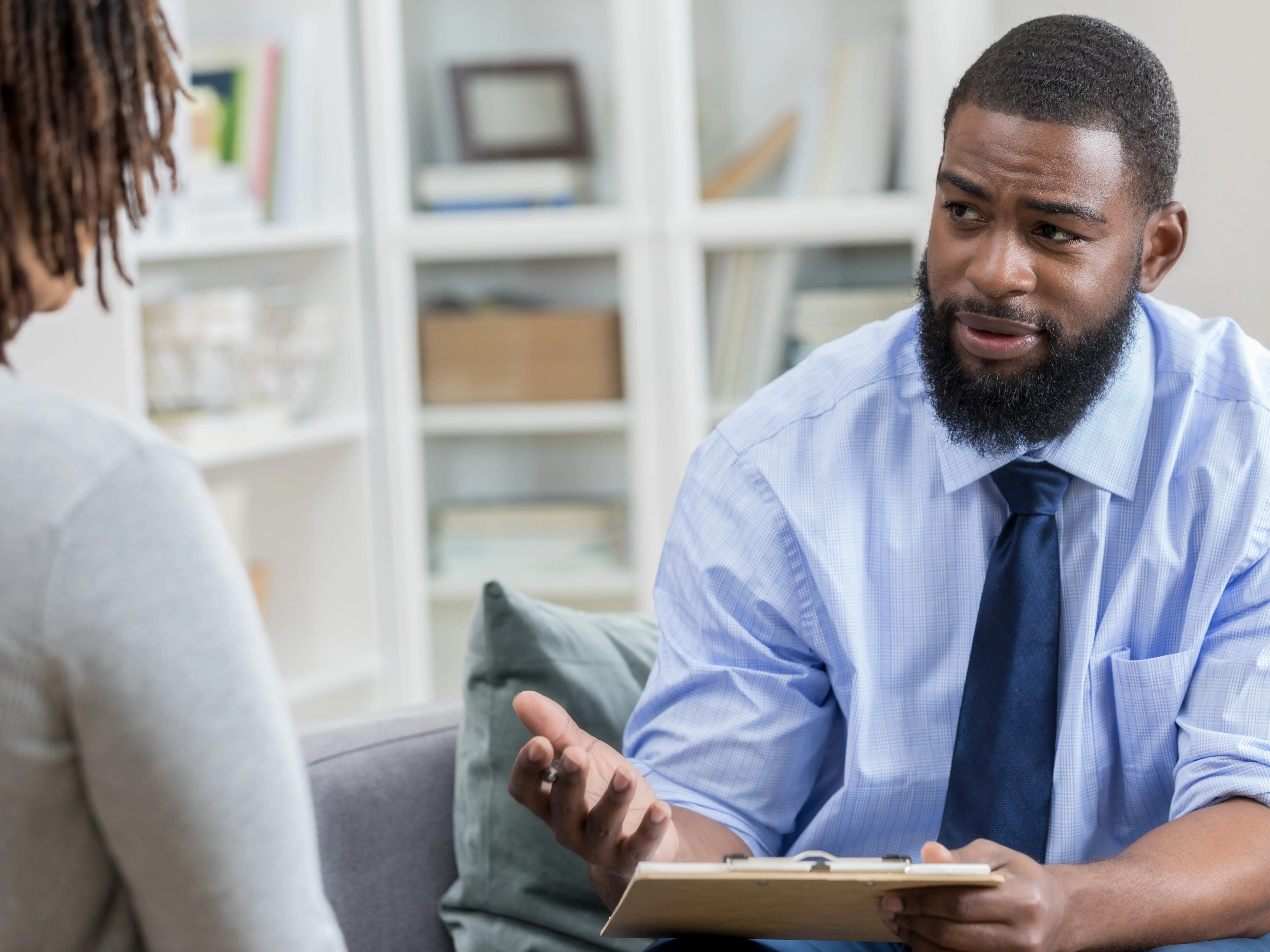 A person wearing a tie and a dress shirt is talking to someone else