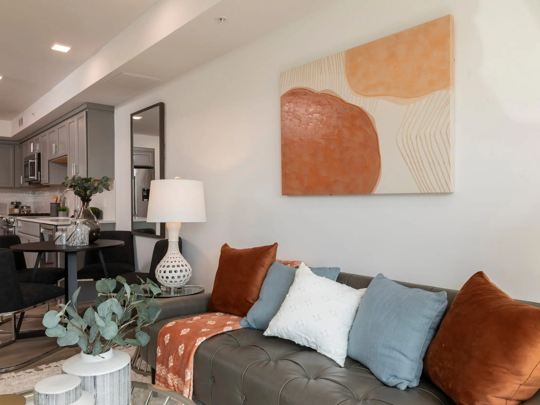 A living room decorated with art and pillows in shades of orange and blue.
