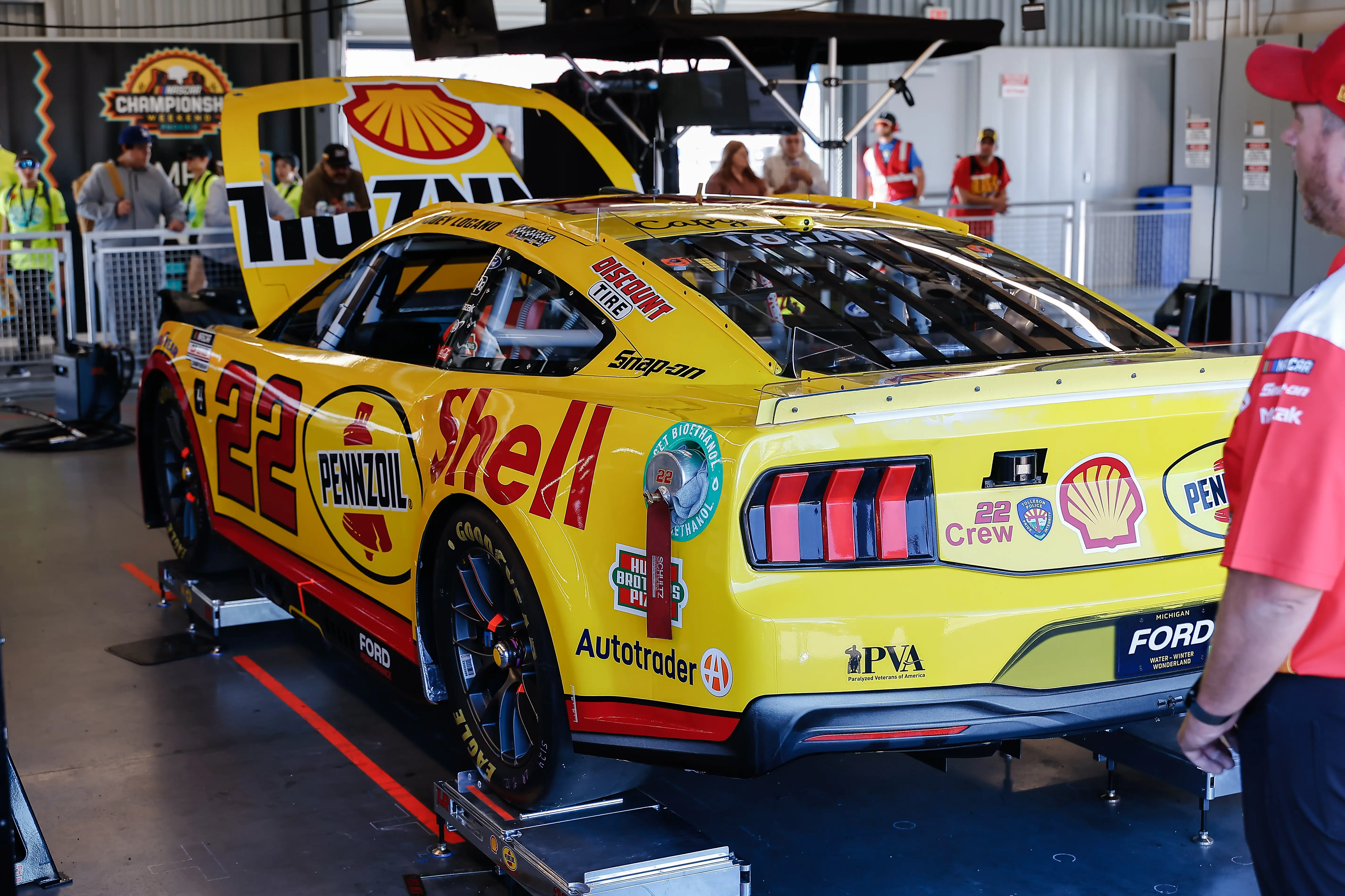 A yellow Ford Mustang, used during NASCAR races, is displayed before a race.
