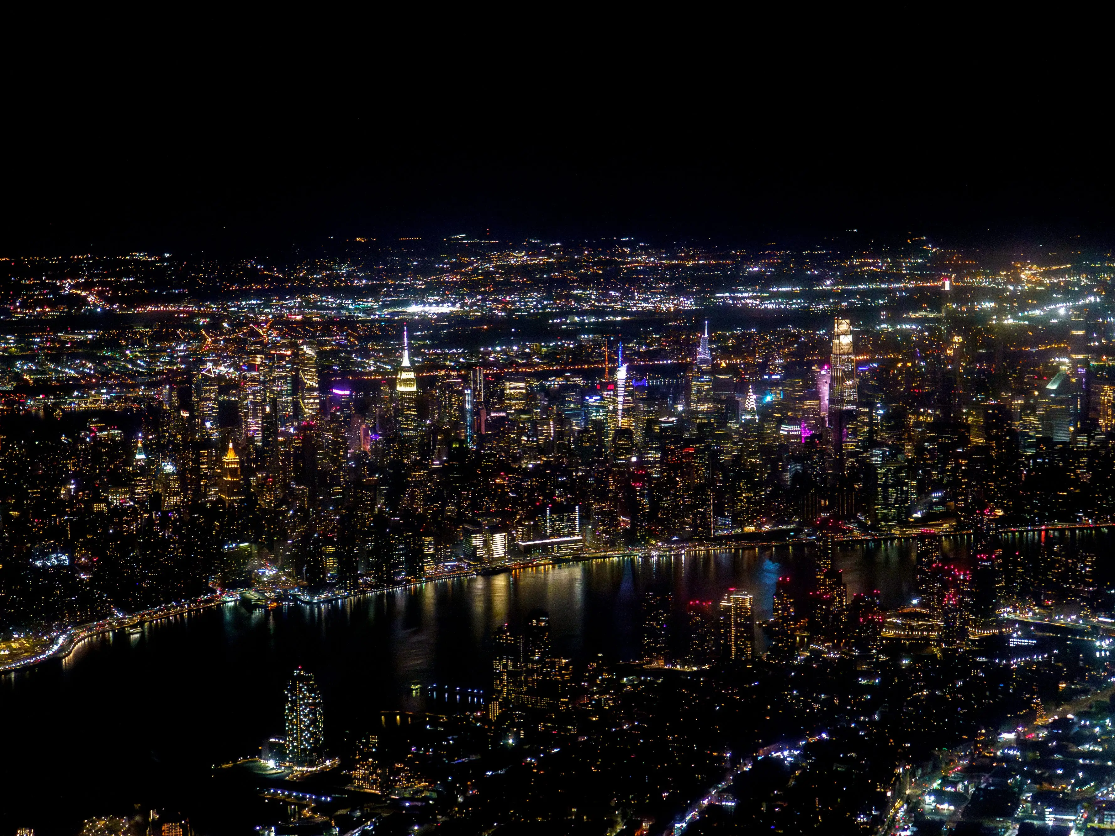 An aerial view of New York City at night from a plane window
