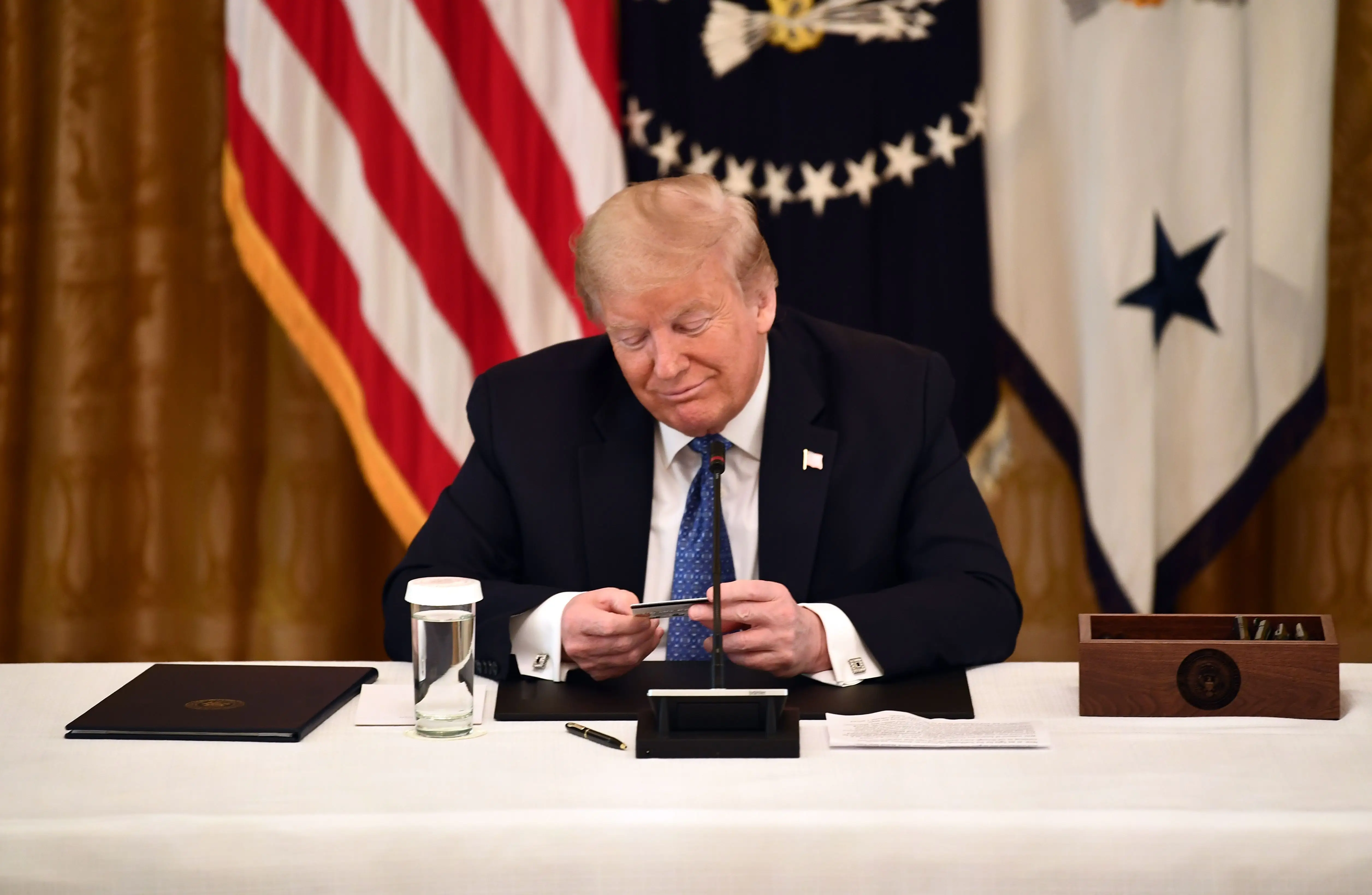 US President Donald Trump looks at a pre-paid debit card during a meeting with his cabinet on May 19, 2020 in the Cabinet Room of the White House in Washington, DC. - The card will be issued by the Internal Revenue Service to distribute nearly 4 million dollars in stimulus aid during the coronavirus pandemic. (Photo by Brendan