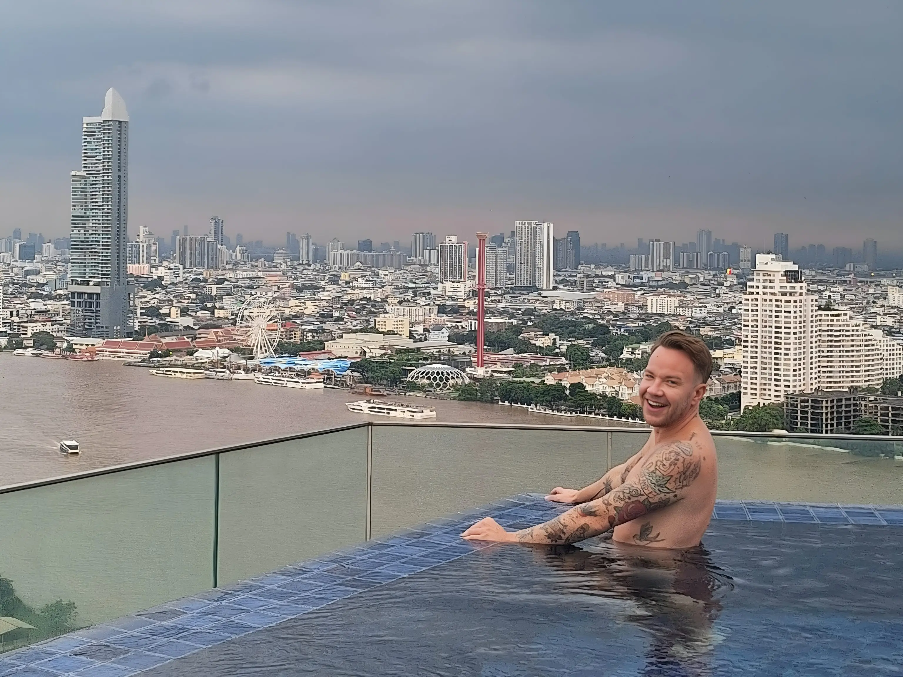 Andre Neveling swimming in a rooftop bar with Bangkok, Thailand in the background.