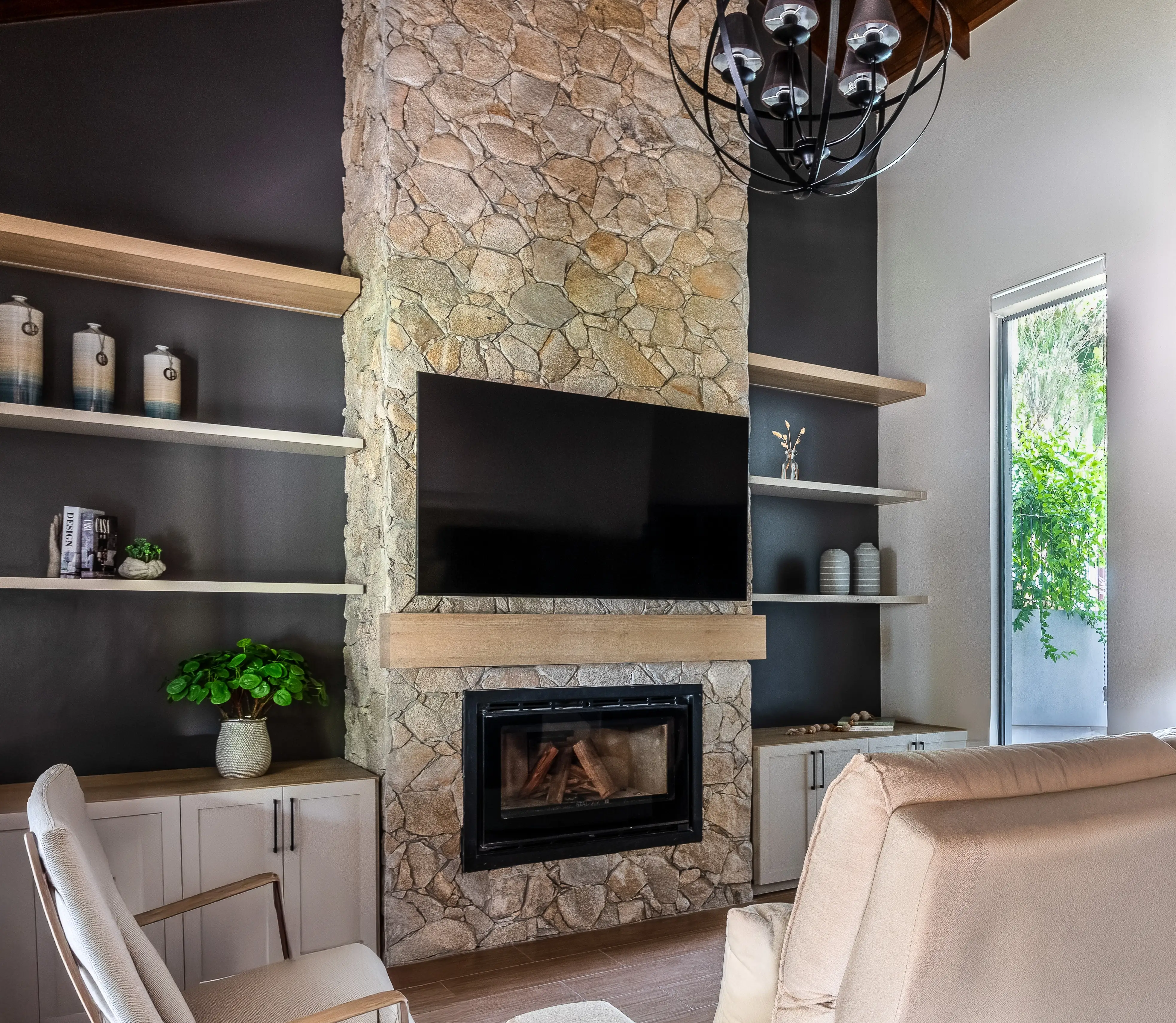TV mounted above fireplace on stone with built-in shelving on either side