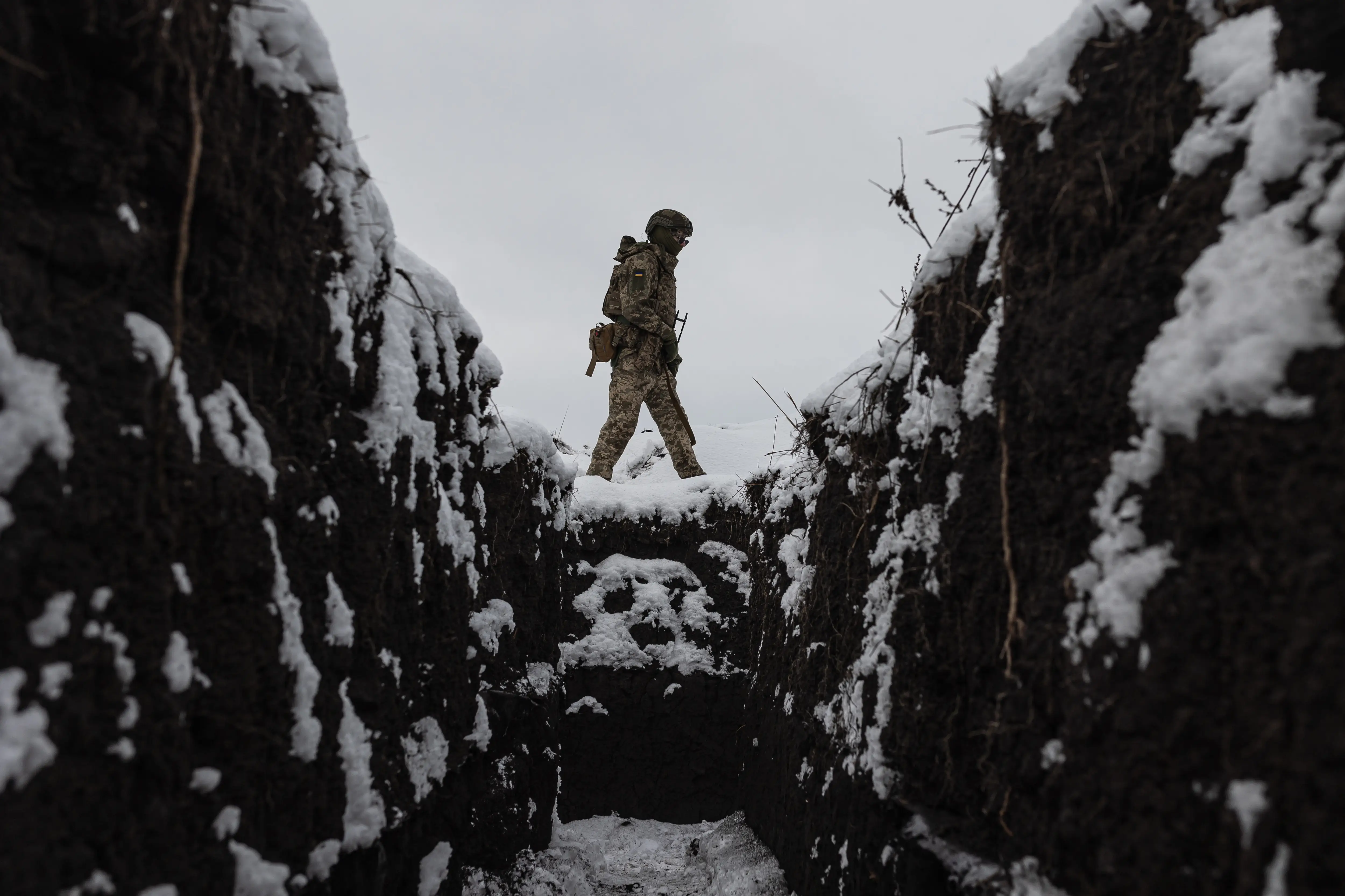 A Ukrainian soldier walks above a snow-covered trench in Kharkiv.